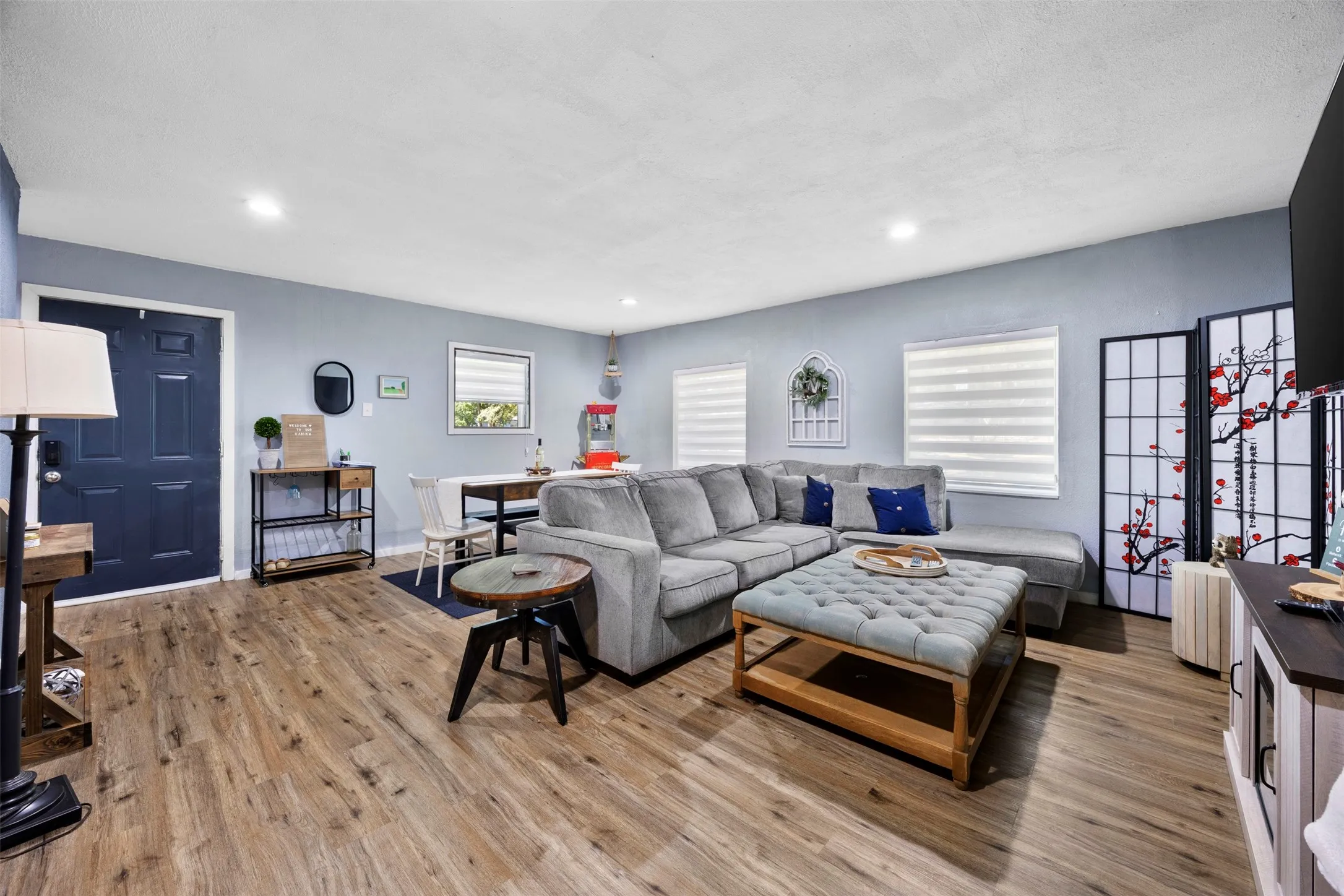 Open-concept living area featuring wood-finish flooring, recessed lighting, and light blue wall tones