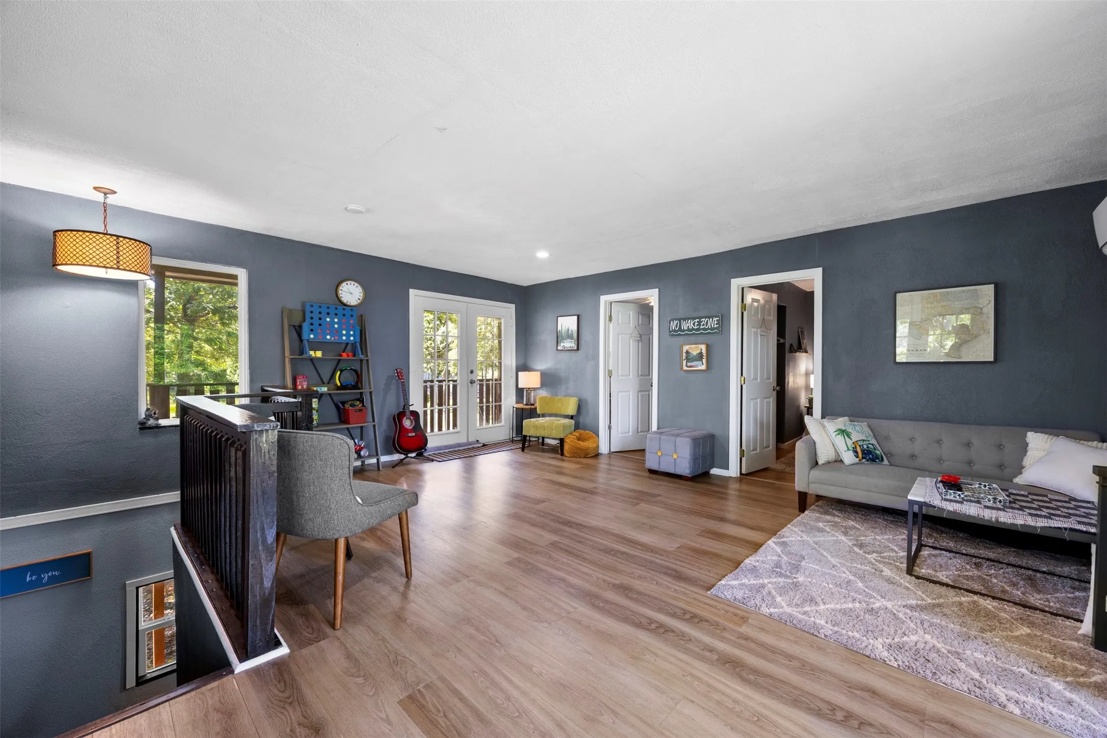 Upper-level space featuring wood-finish flooring, a contemporary drum pendant light, and a white ceiling