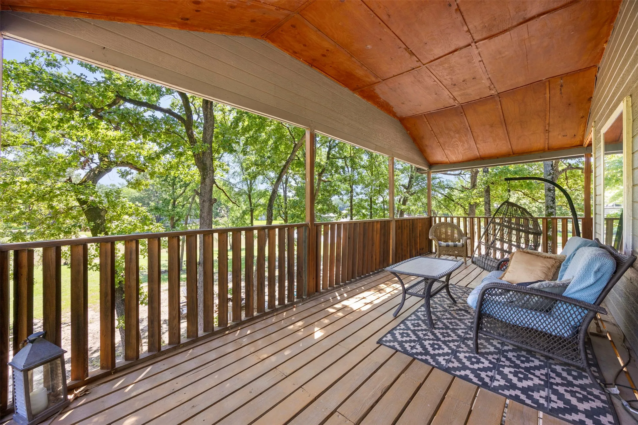Covered outdoor deck with light wood flooring