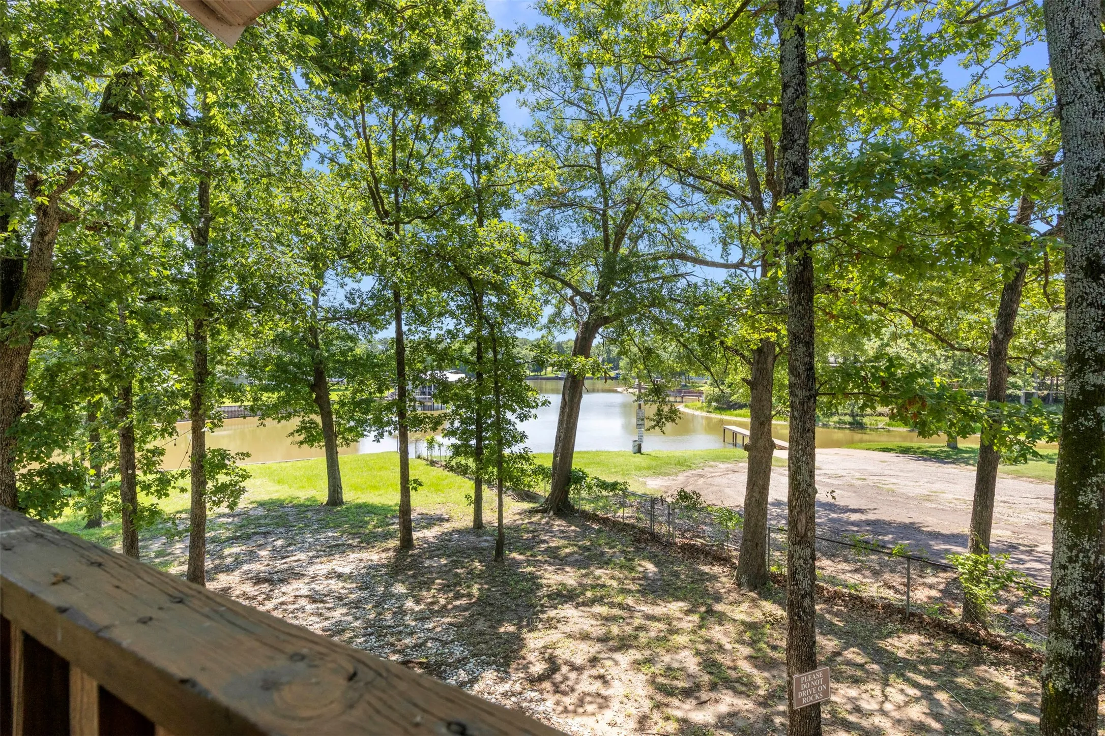 Wood-finish deck railing overlooking a treed property with water frontage