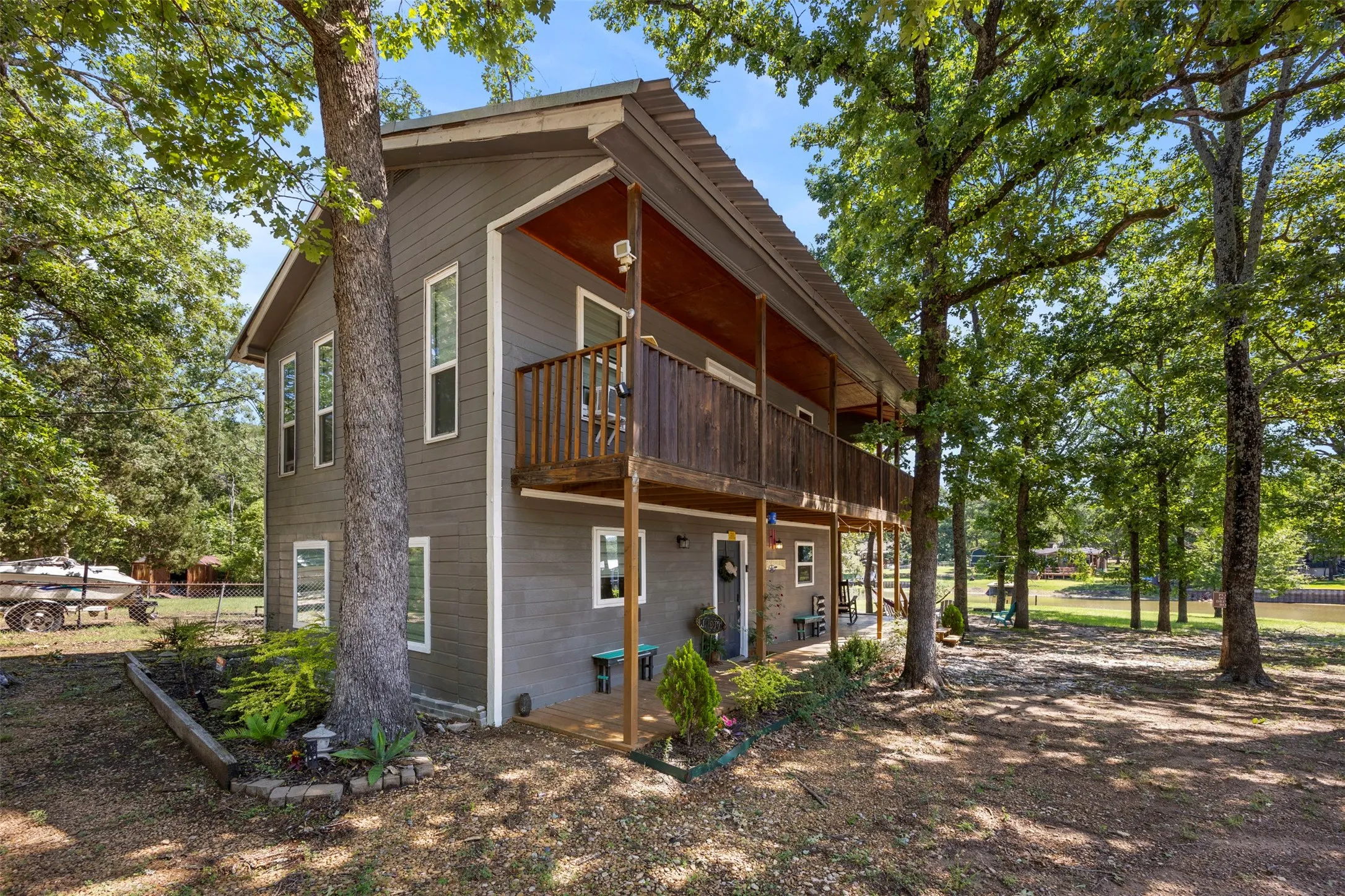 Two-story residence featuring gray siding with white trim, a metal roof, and a full-length balcony