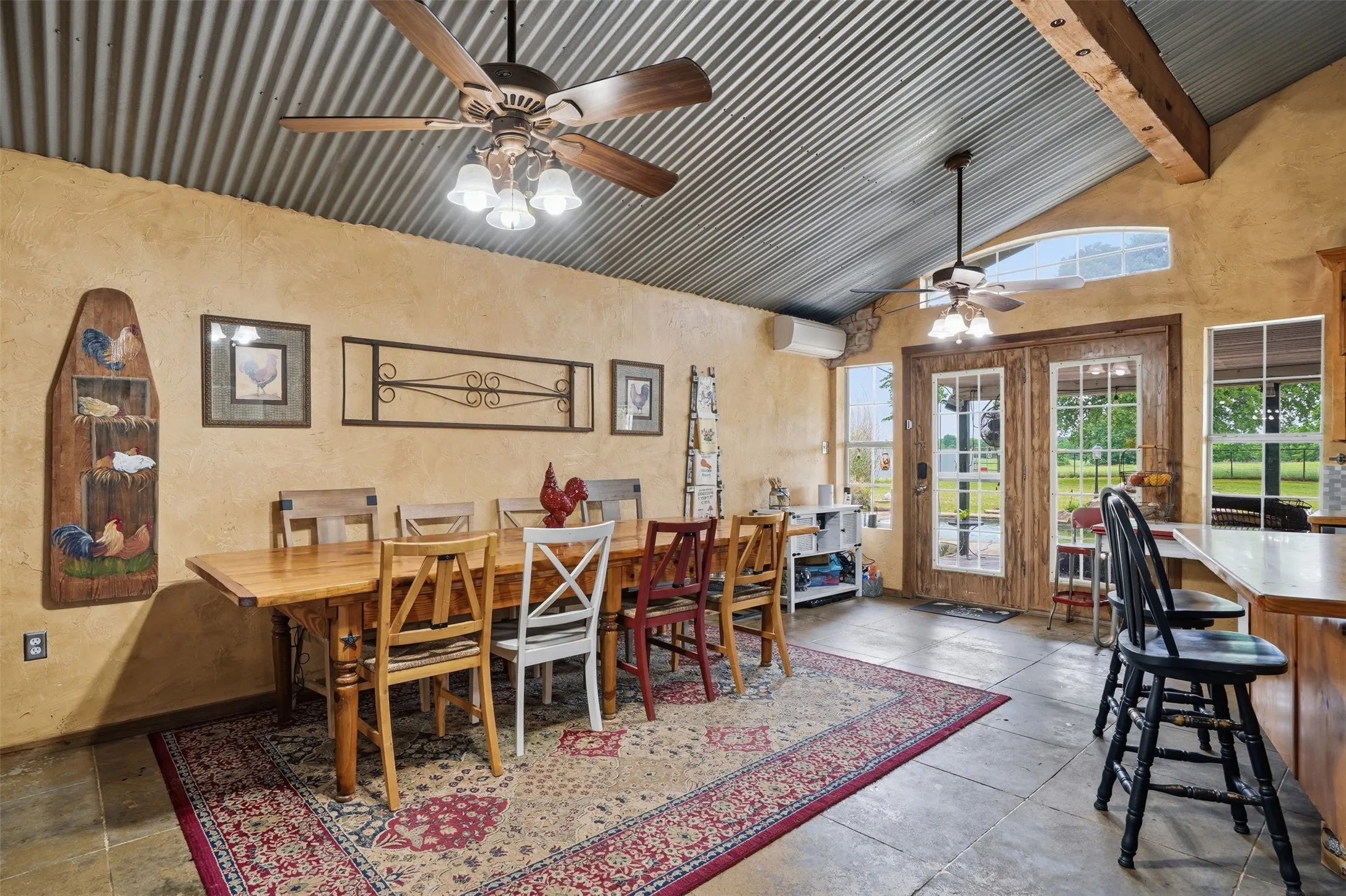 Vaulted corrugated metal ceiling with exposed wood beams, featuring a ceiling fan with integrated lighting