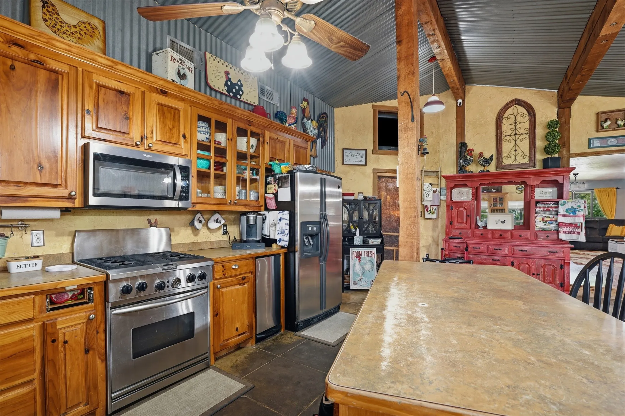 Kitchen featuring extensive wood cabinetry, stainless steel appliances, a built-in microwave, and a ceiling fan