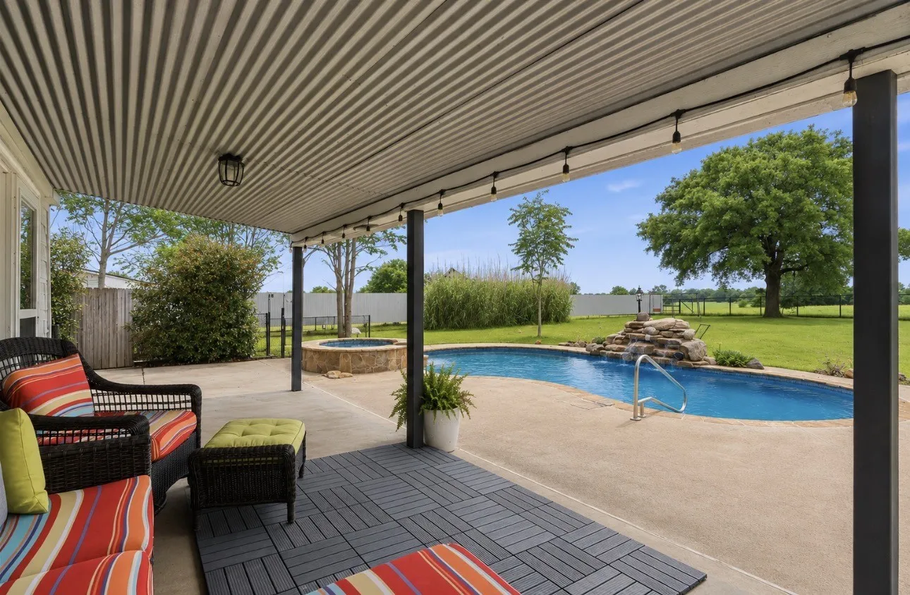 Covered patio featuring a corrugated metal ceiling, string lighting, and dark gray modular flooring