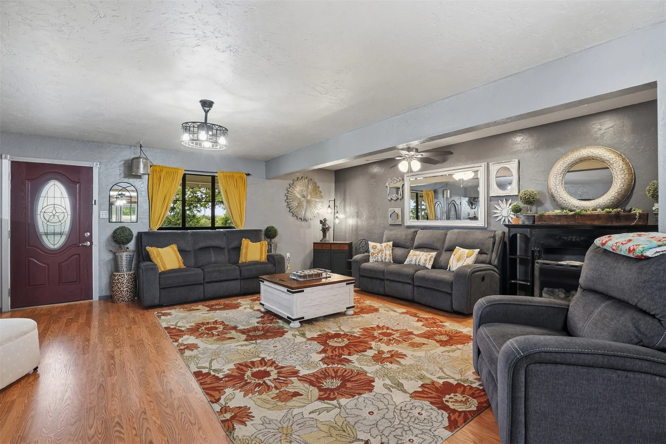 Spacious living area featuring wood-finish flooring, a decorative entry door with an oval glass insert, and a modern ceiling fan with integrated lighting