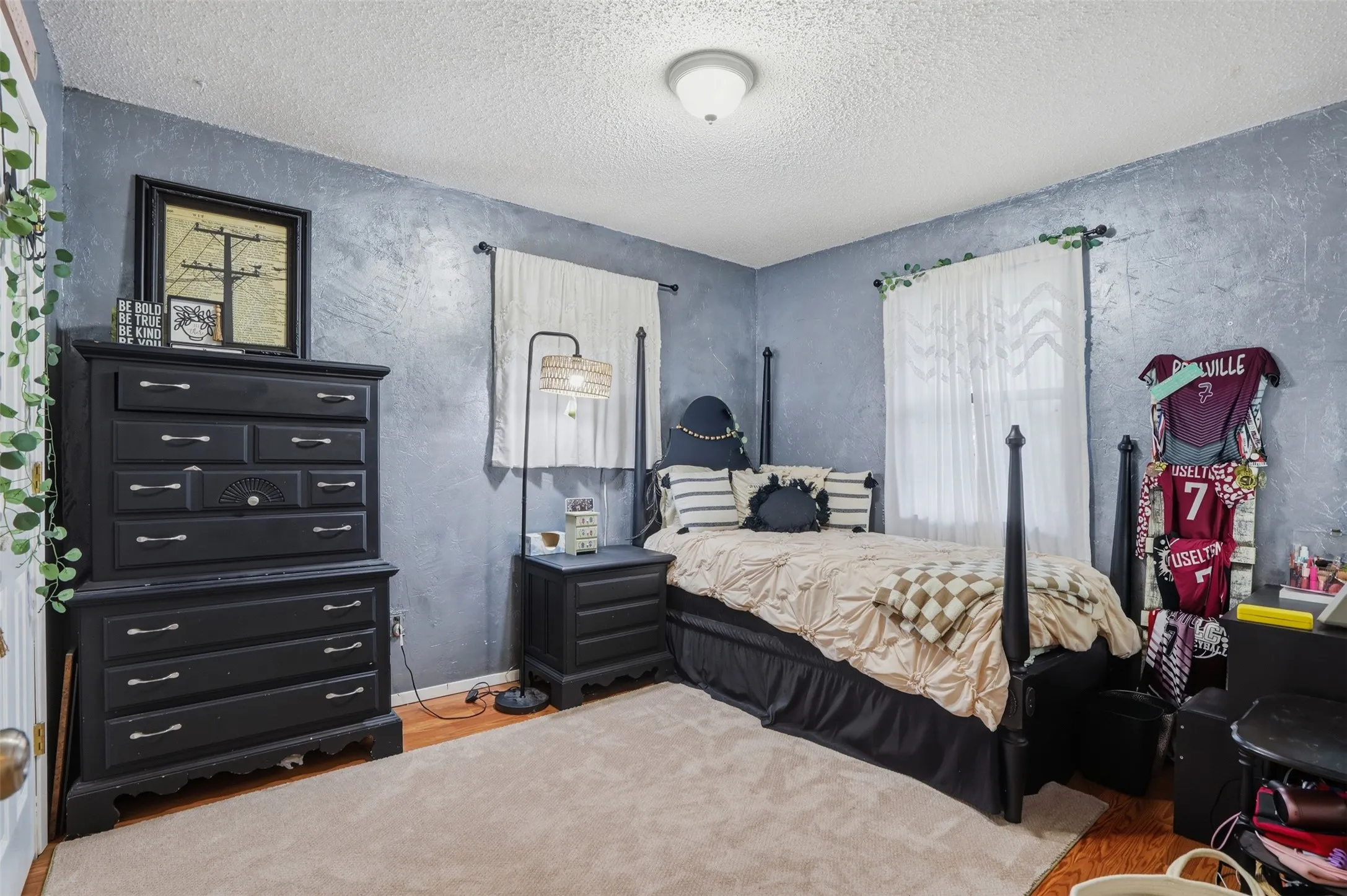 Room featuring textured walls, wood-finish flooring, and a ceiling-mounted light fixture