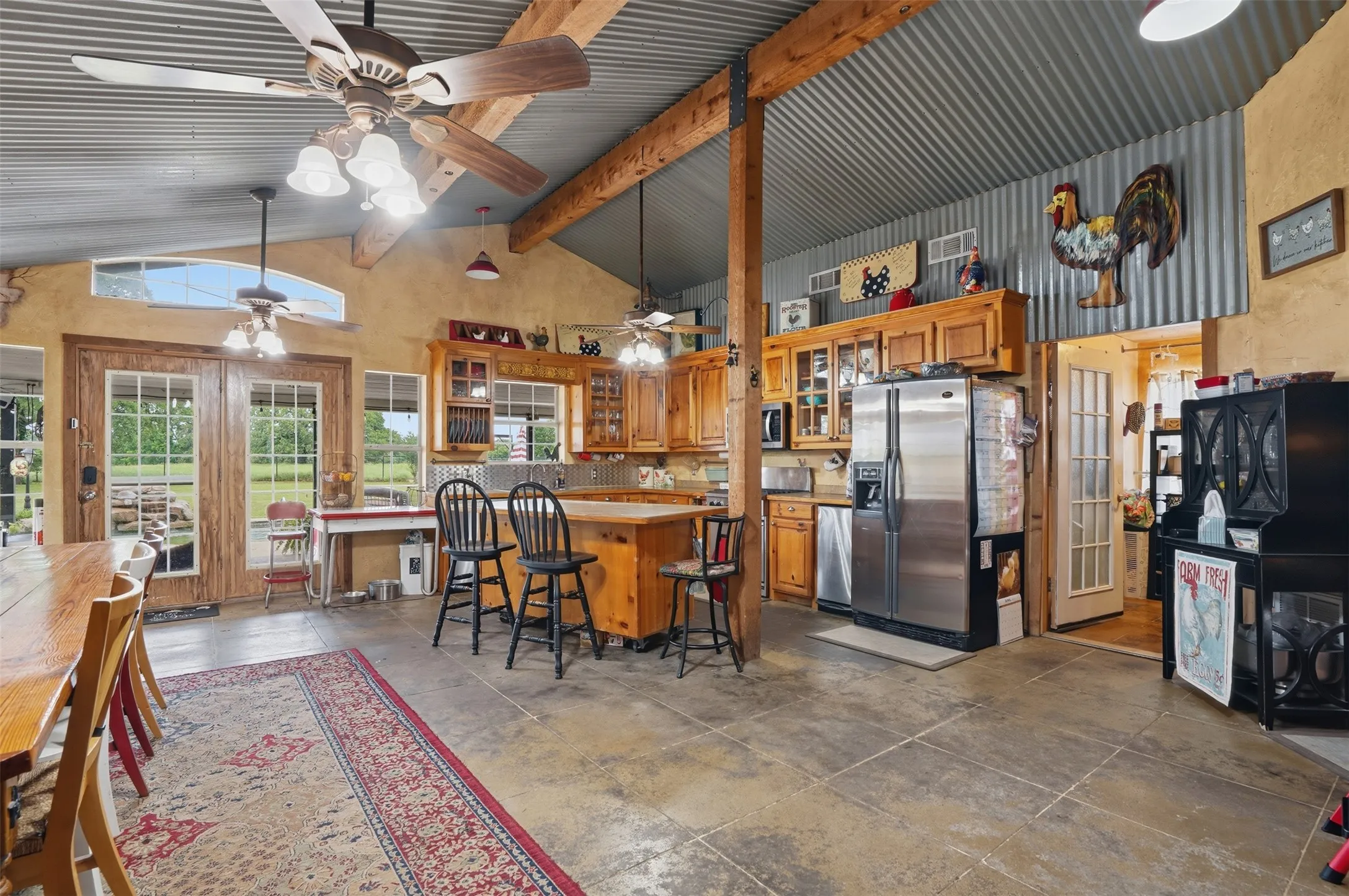 Open-concept living area featuring exposed wood beams, polished concrete flooring, and a corrugated metal accent wall