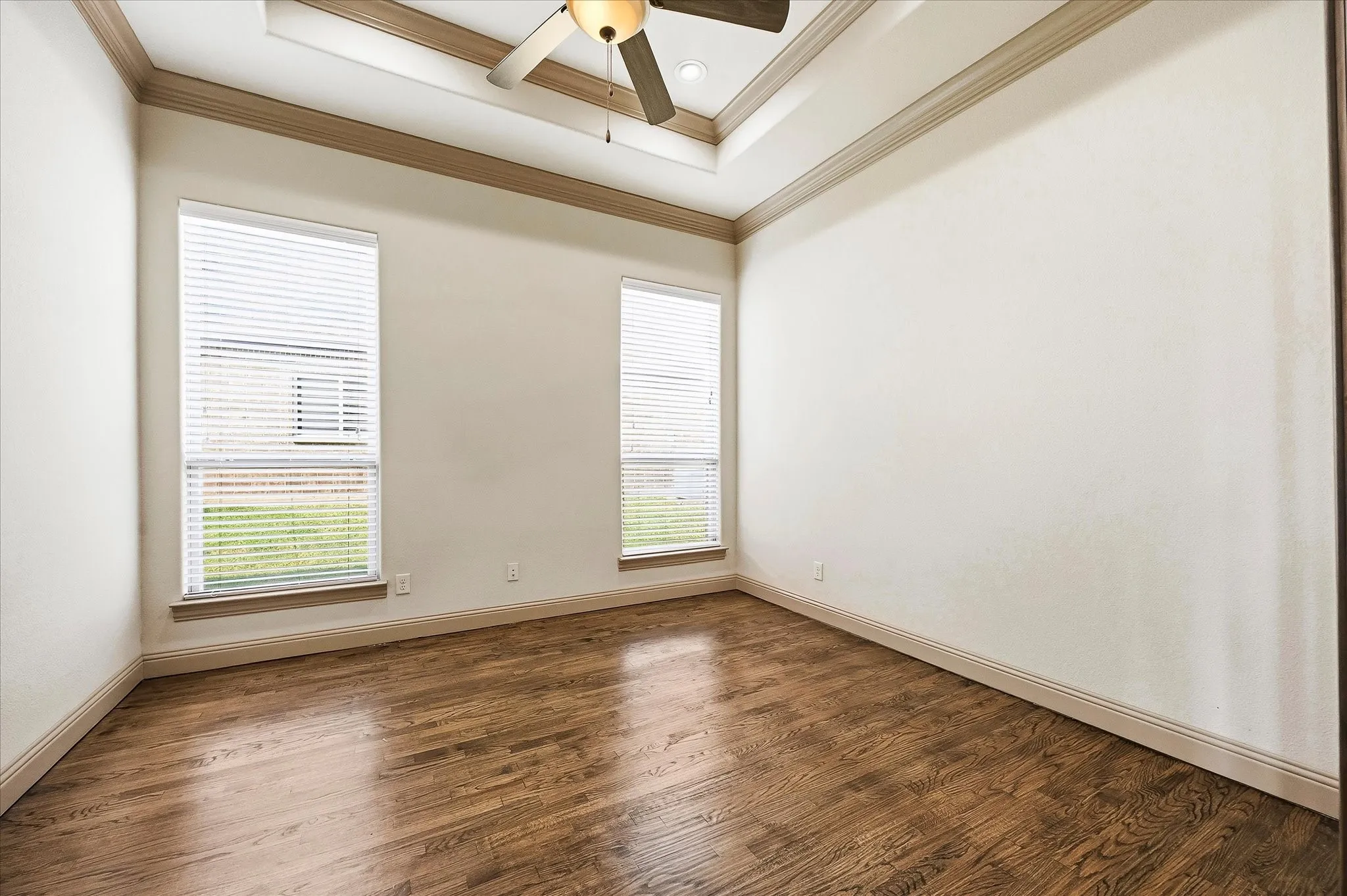 Lovely office includes tiered ceiling and hardwood floors