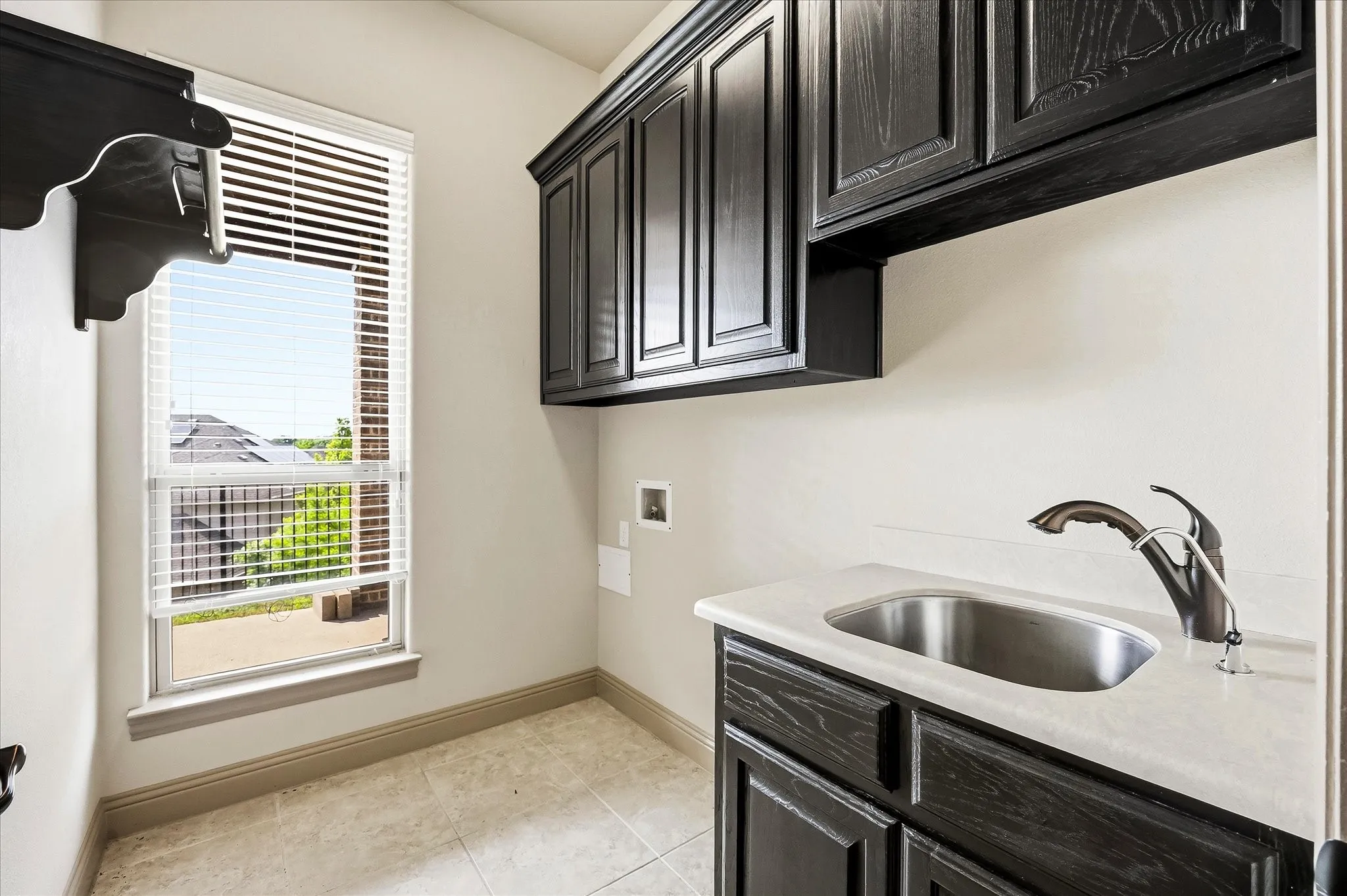 Utility room includes custom cabinetry, sink and folding area.