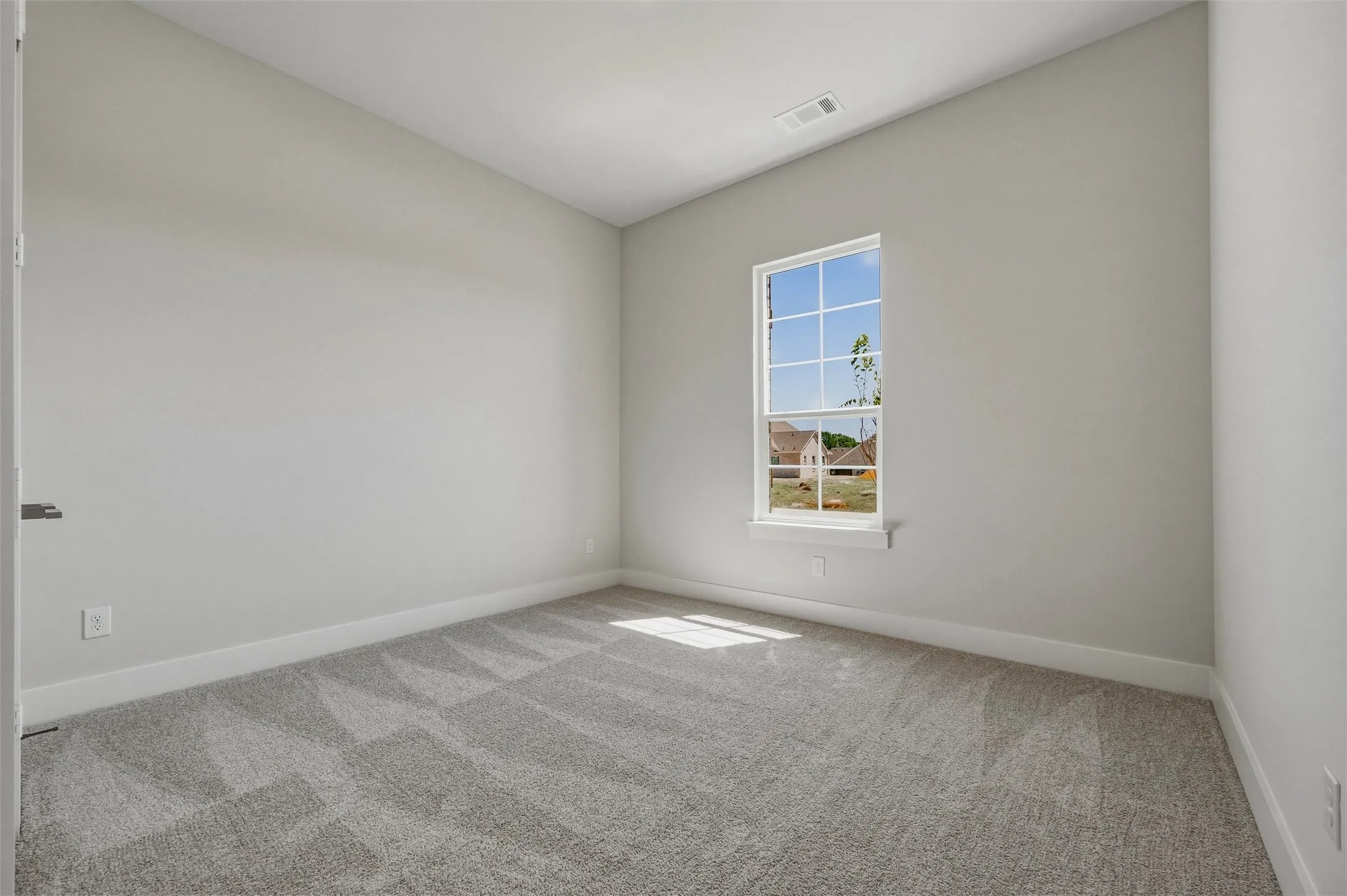 Plush gray carpeting, neutral wall palette, and a white-trimmed window