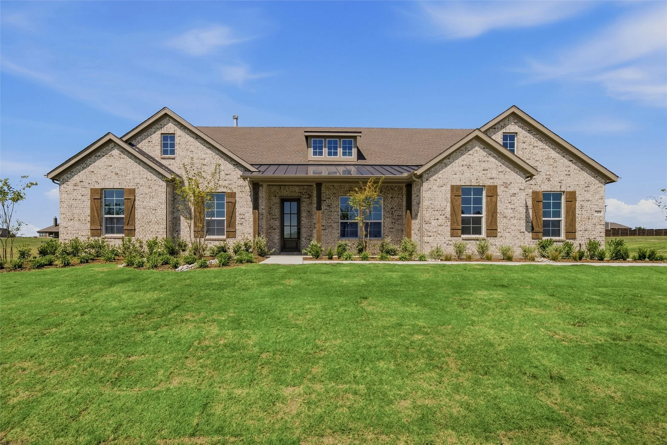 Brick exterior with contrasting dark window shutters, gabled rooflines, dark framed windows, and a covered entry