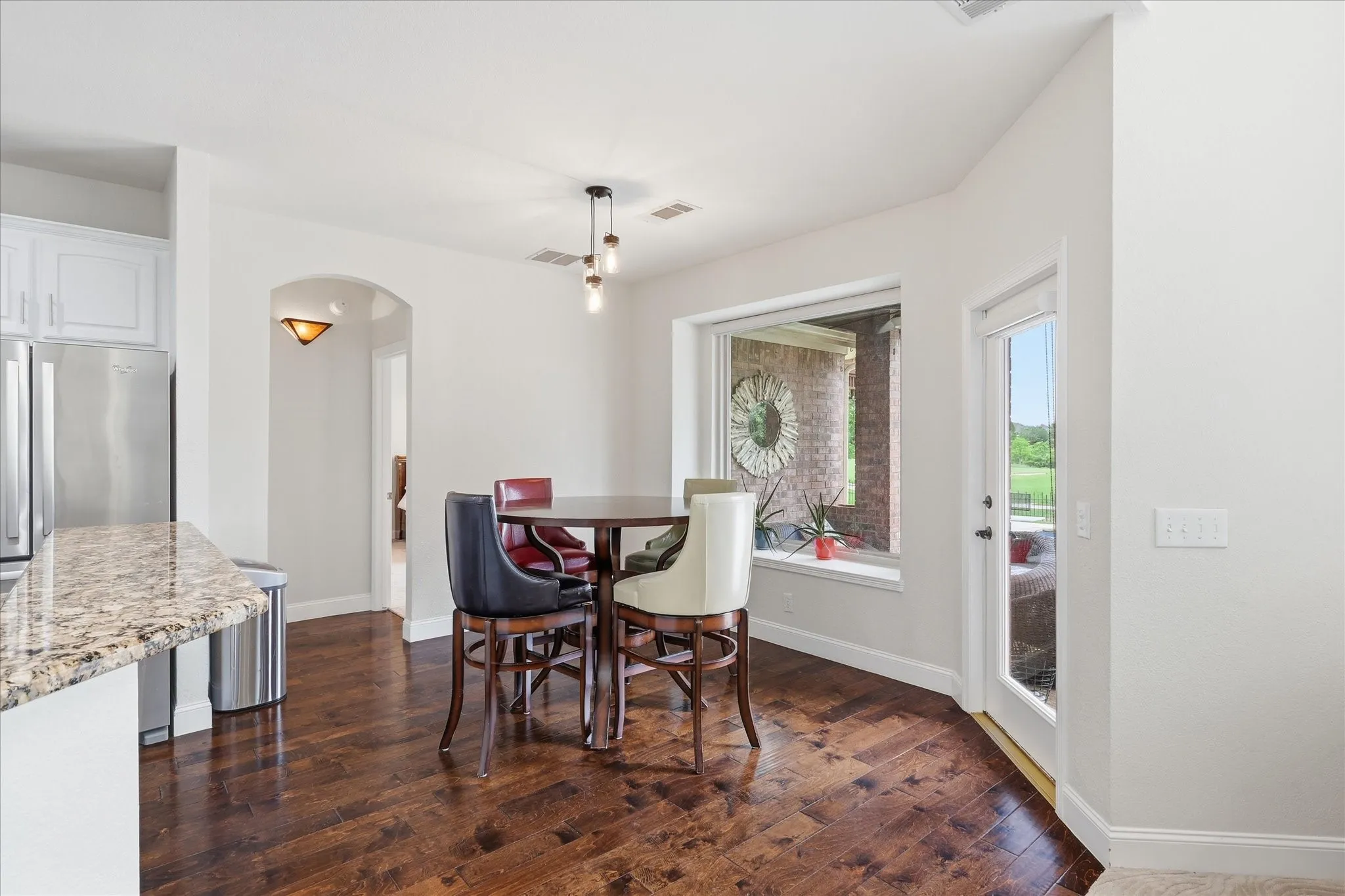 Kitchen dining nook featuring wood-finish flooring, a contemporary pendant light fixture, a wide window, and a glass-paneled door