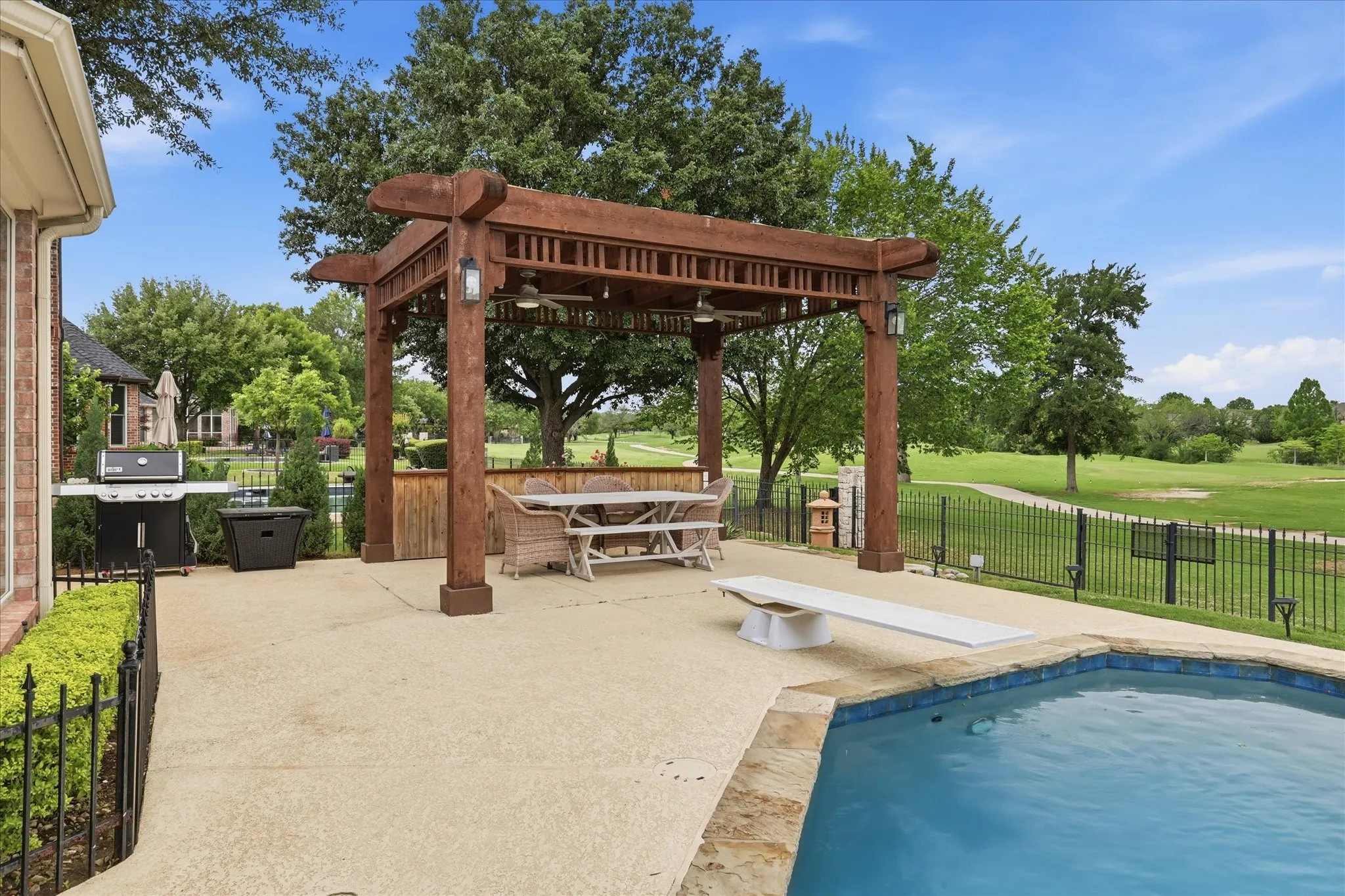 Expansive patio with an integrated swimming pool, diving board, and a substantial wooden pergola