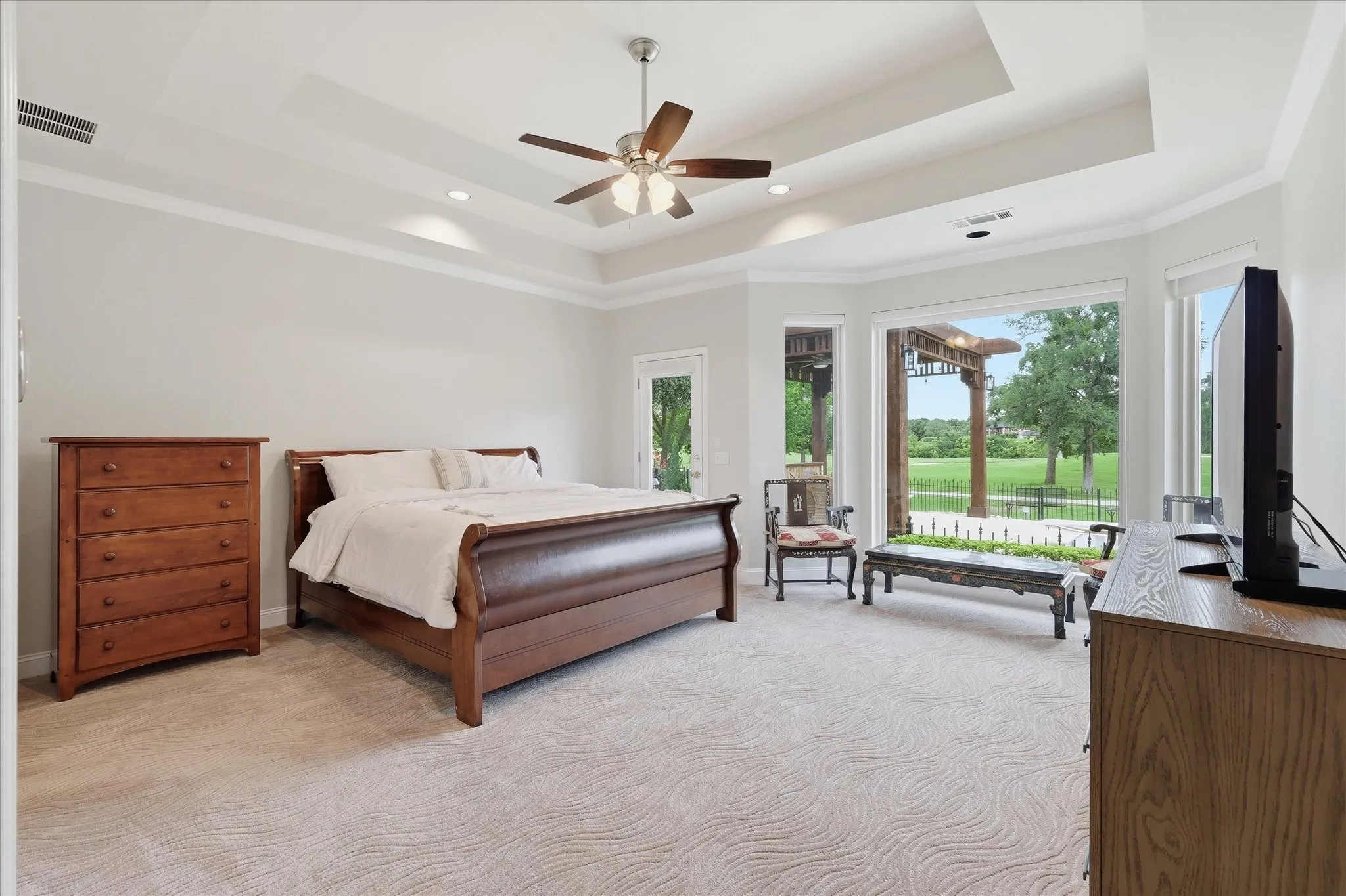 Spacious room featuring a tray ceiling with a ceiling fan, recessed lighting, and crown molding