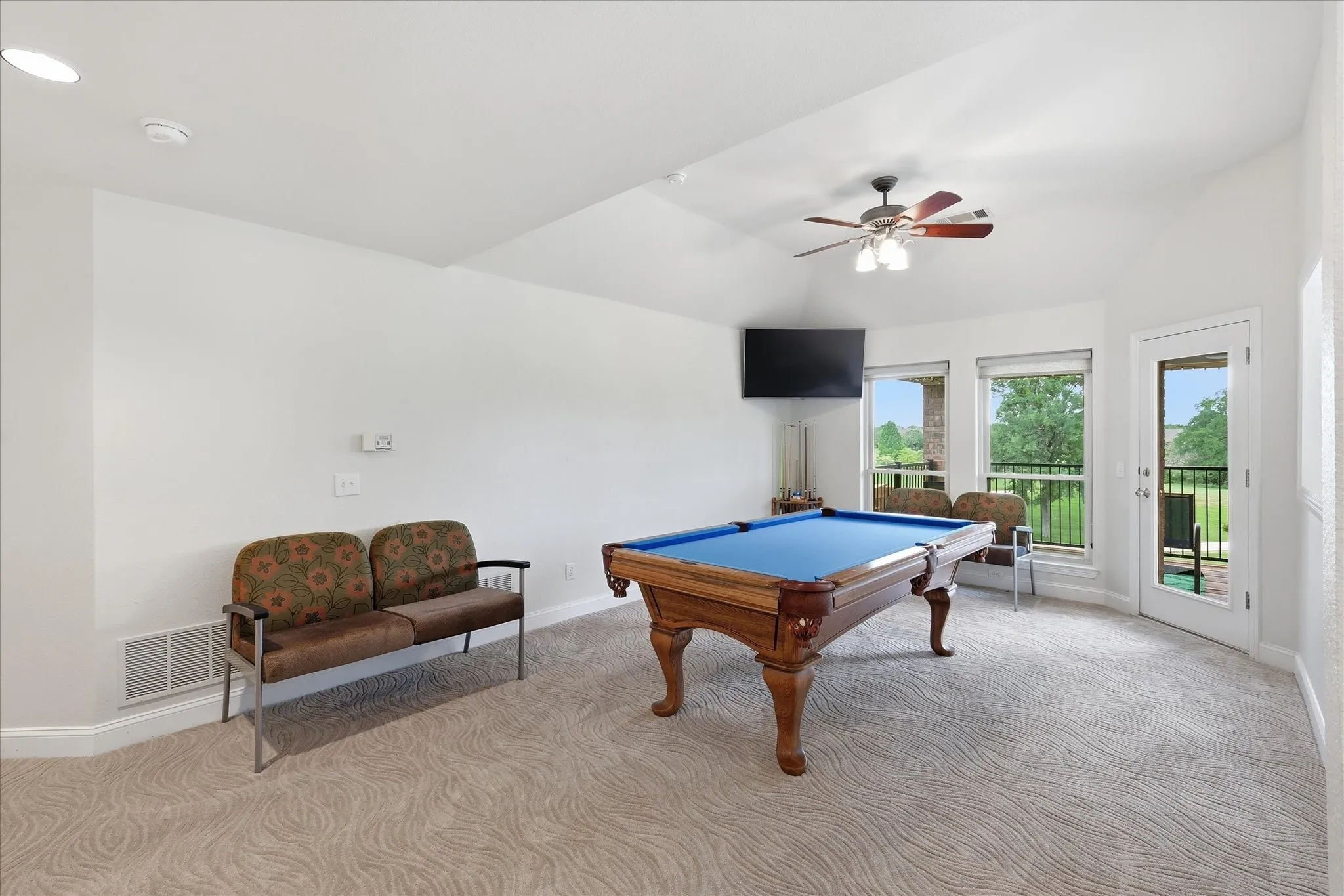 Spacious room featuring vaulted ceilings, a ceiling fan with integrated lighting, and light-toned patterned carpeting