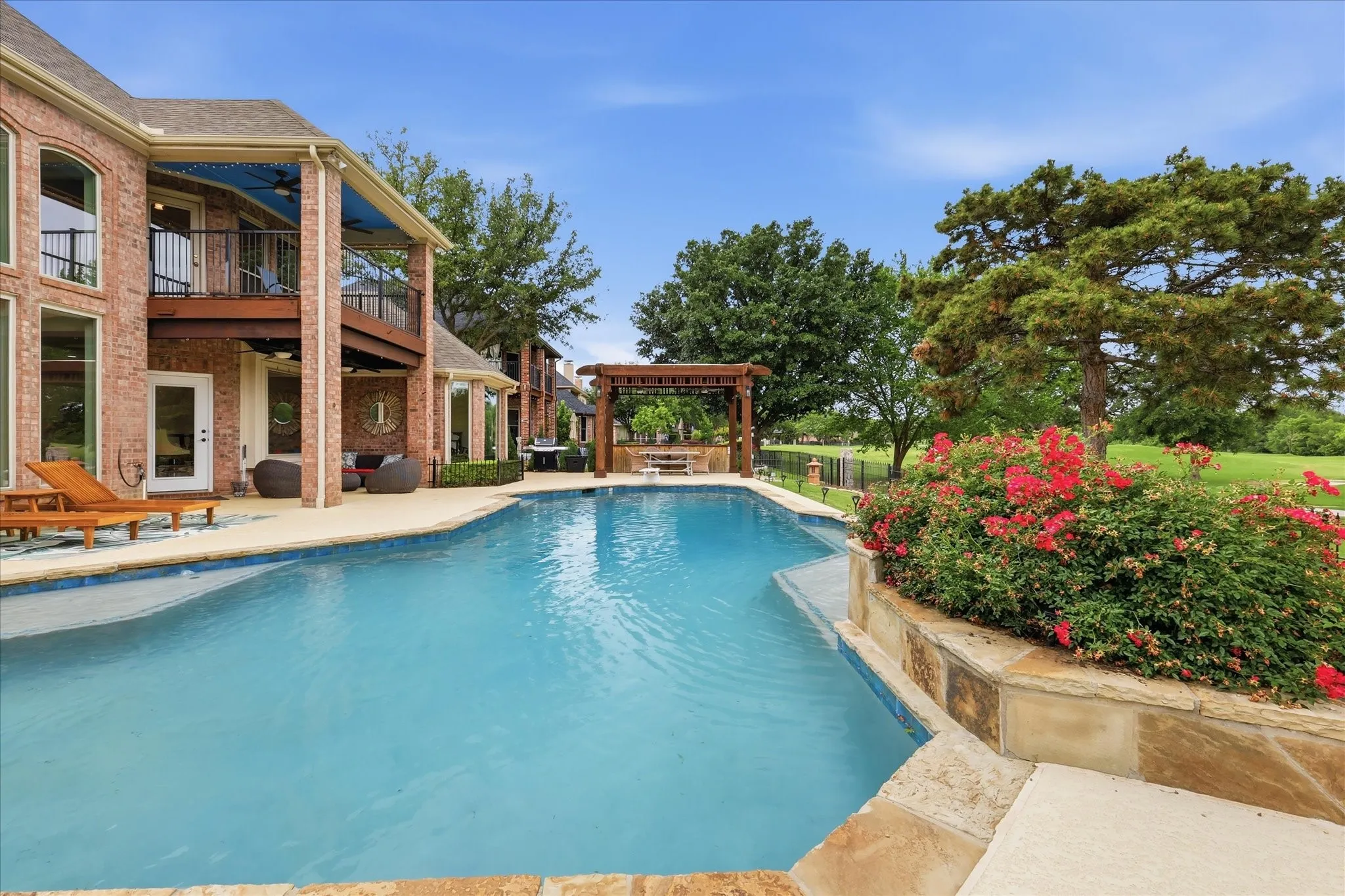 Backyard oasis featuring a large swimming pool, stone coping, and a pergola-covered patio area