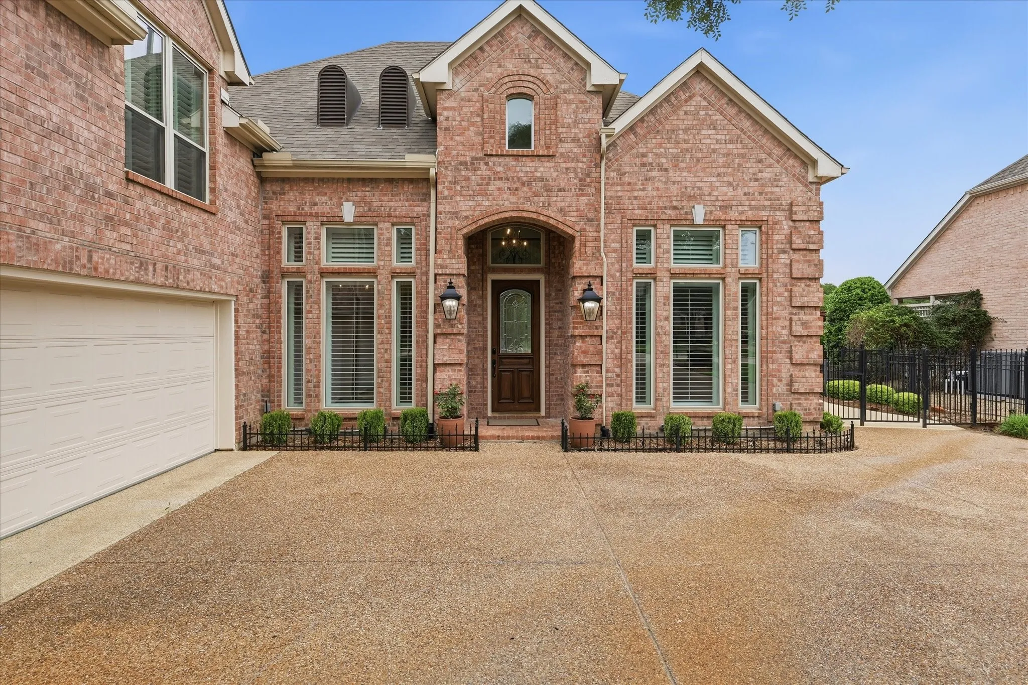 Brick exterior featuring the garage, arched entry, and a dormer roof