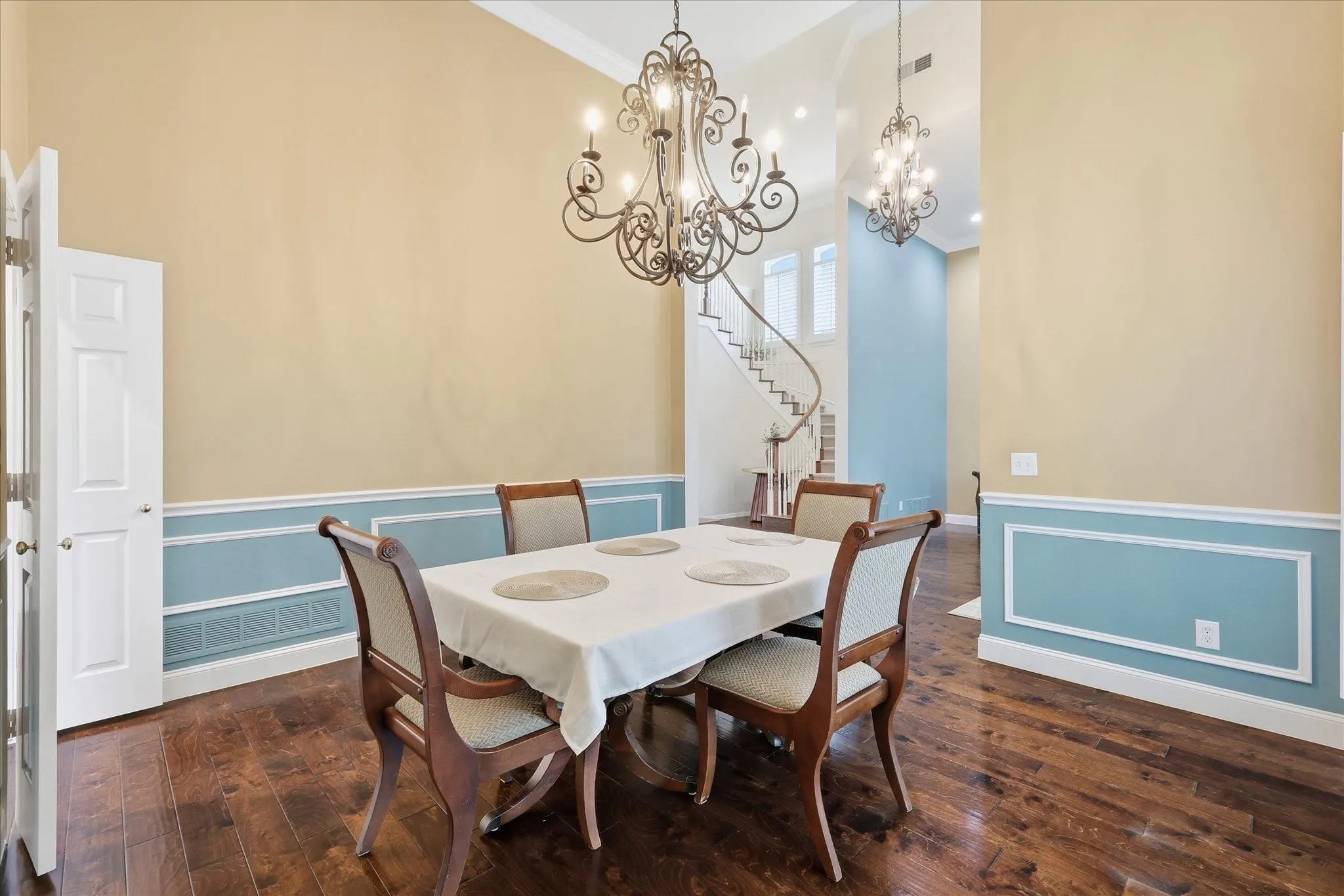 Formal dining area featuring rich wood-finish flooring and a decorative wrought iron chandelier