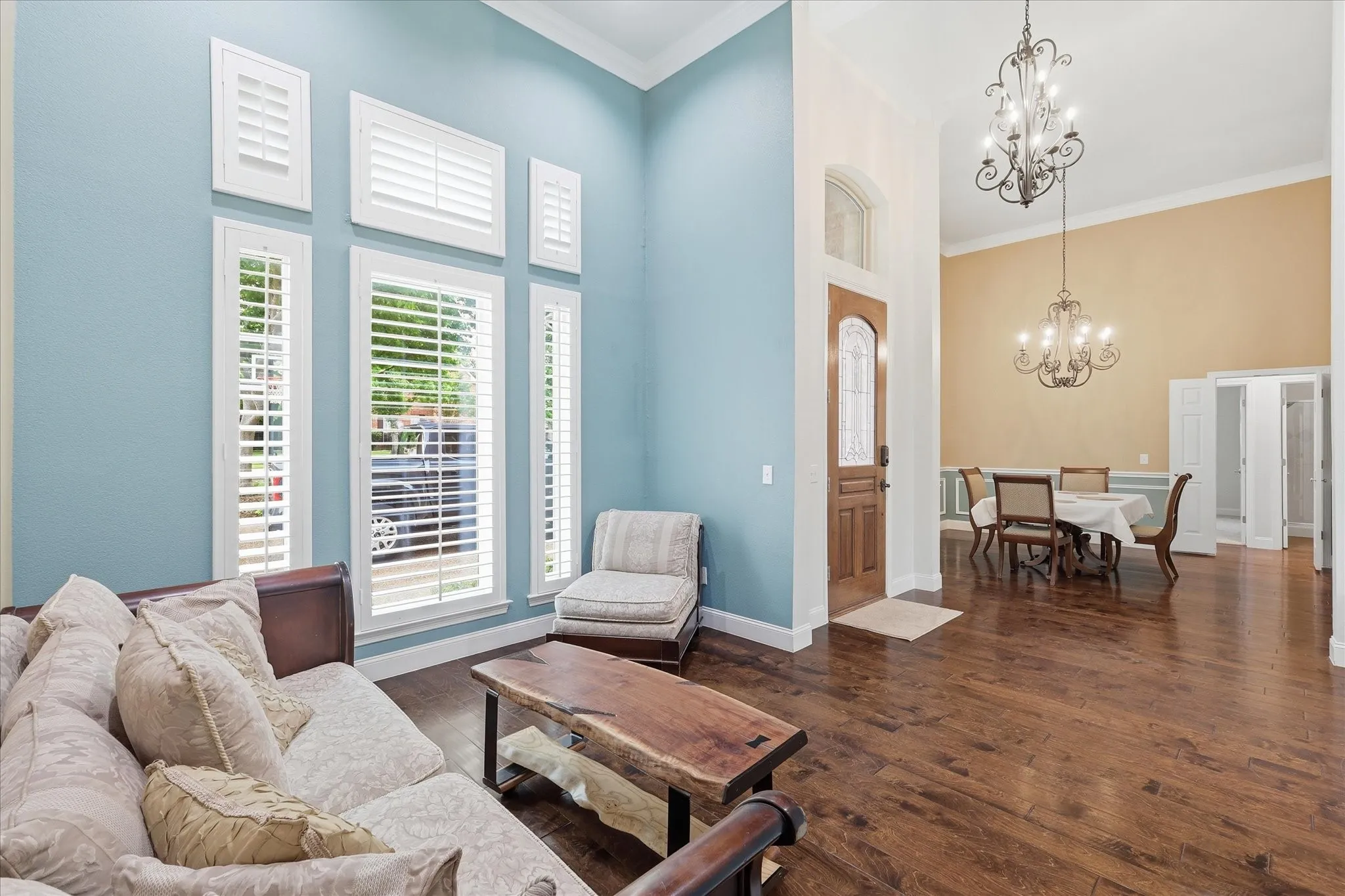 Front Living area featuring wood-finish flooring, high ceilings, and multiple windows with plantation shutters
