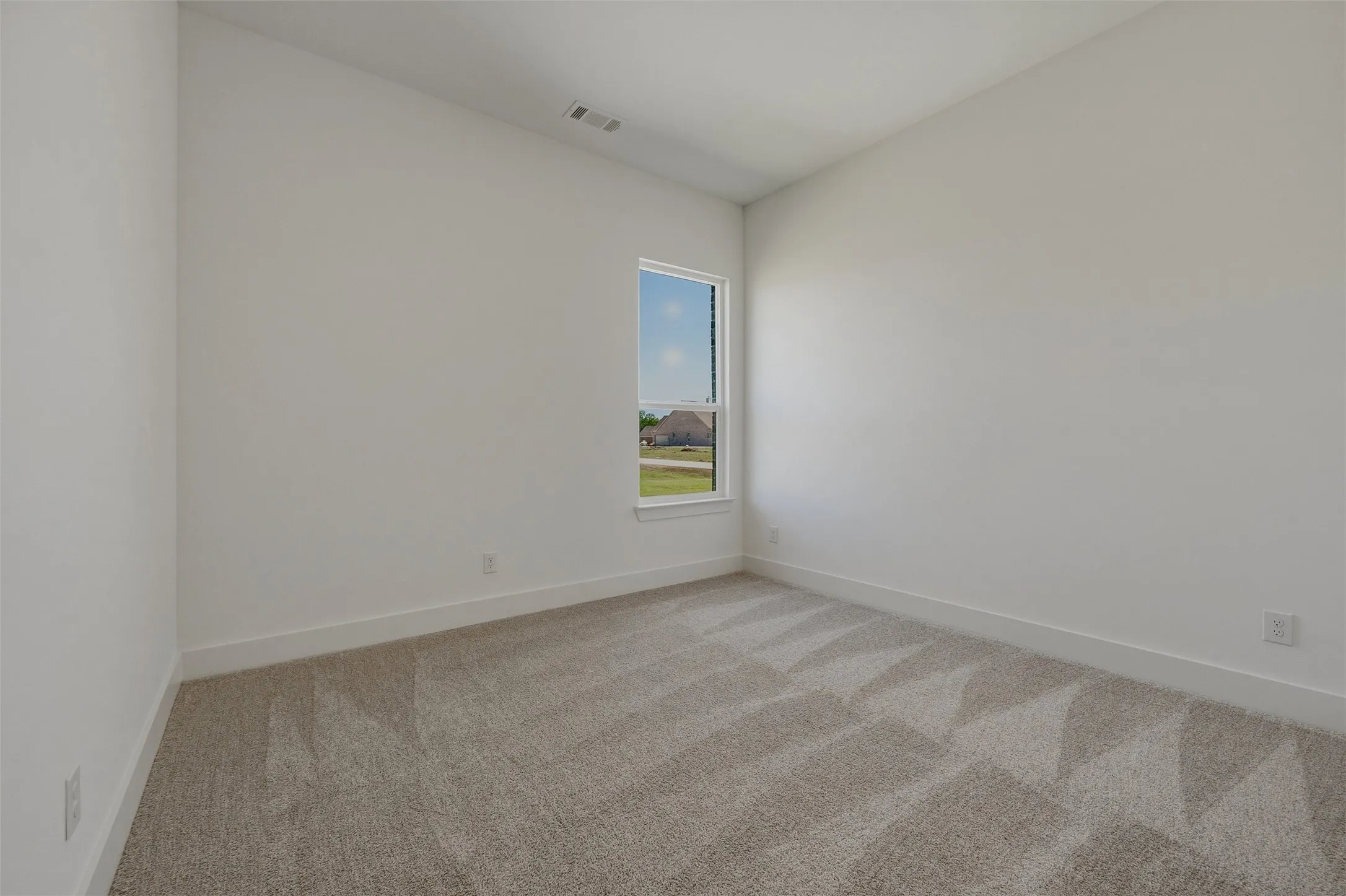 Neutral wall tones, recessed lighting, and a single window with white trim