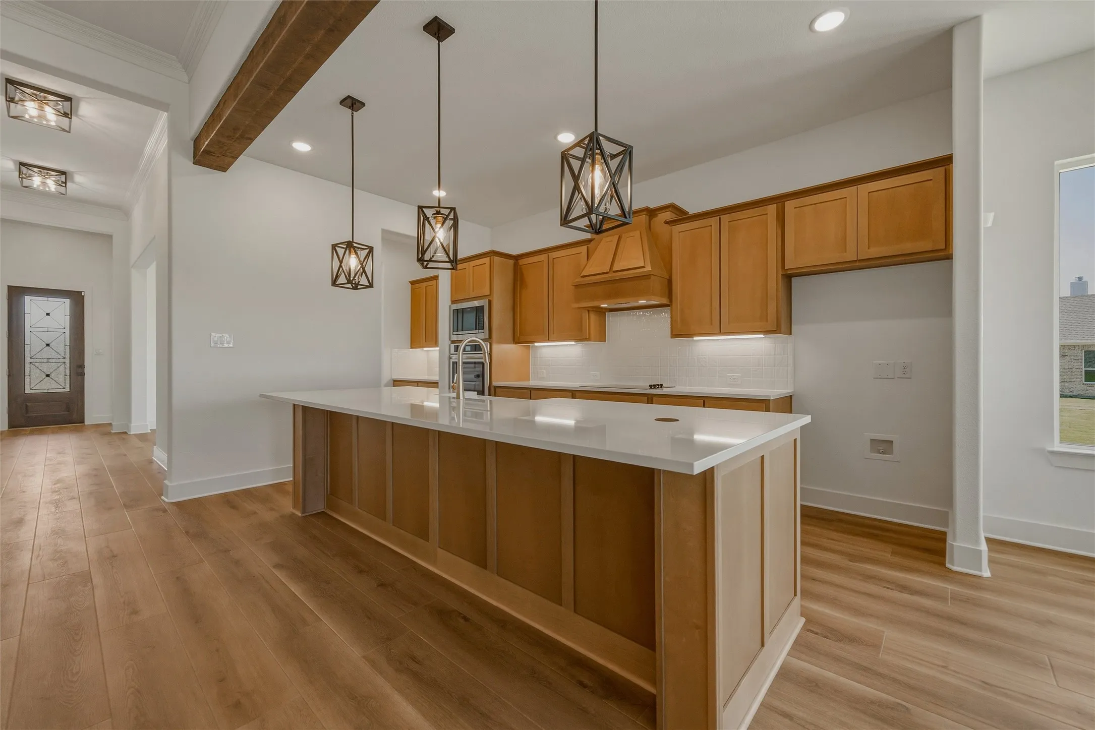 Open-concept kitchen featuring an expansive center island with countertop, wood-finish flooring, and pendant lighting