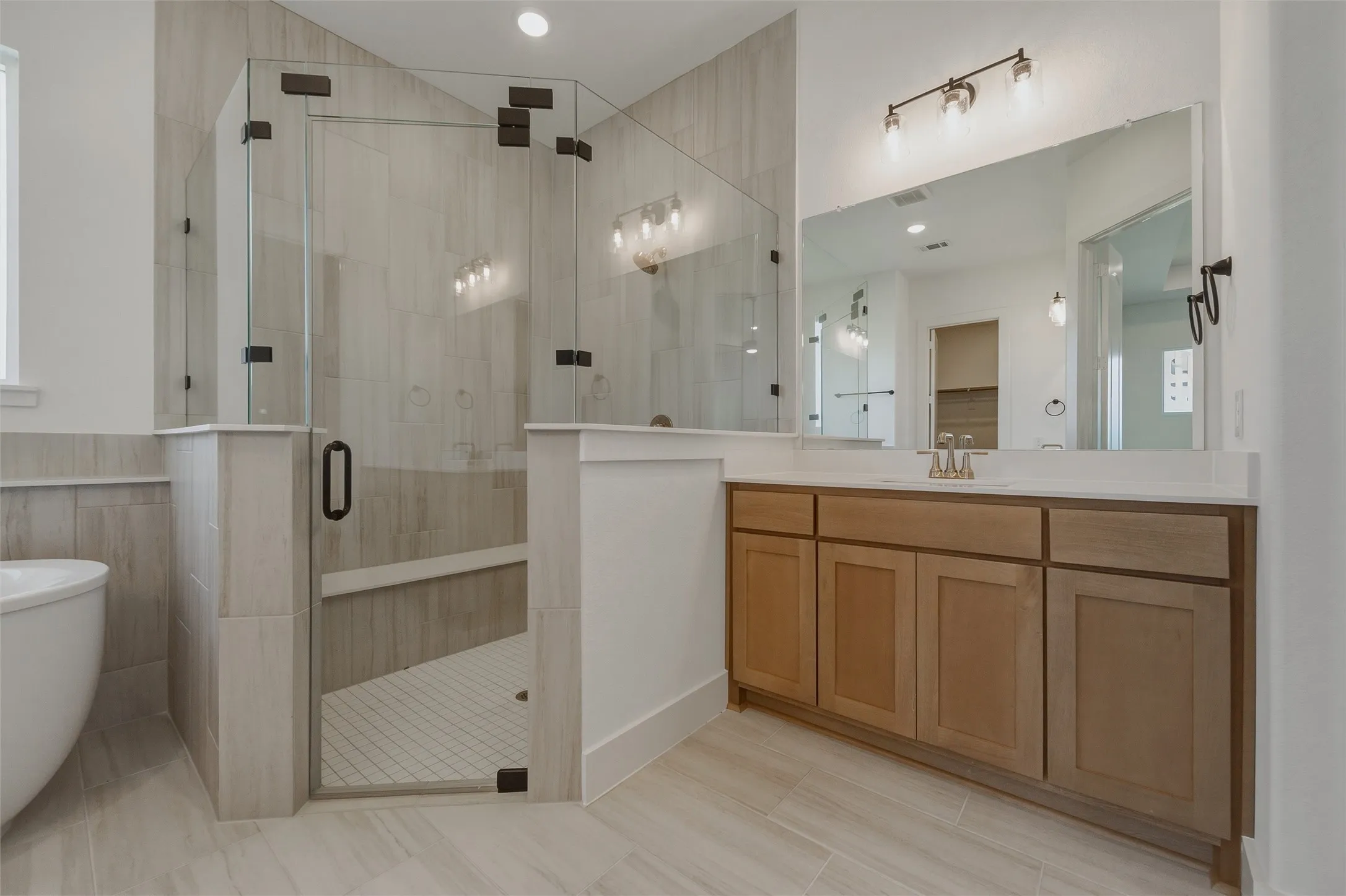 Expansive walk-in shower with clear glass enclosure, integrated bench, and tiled walls