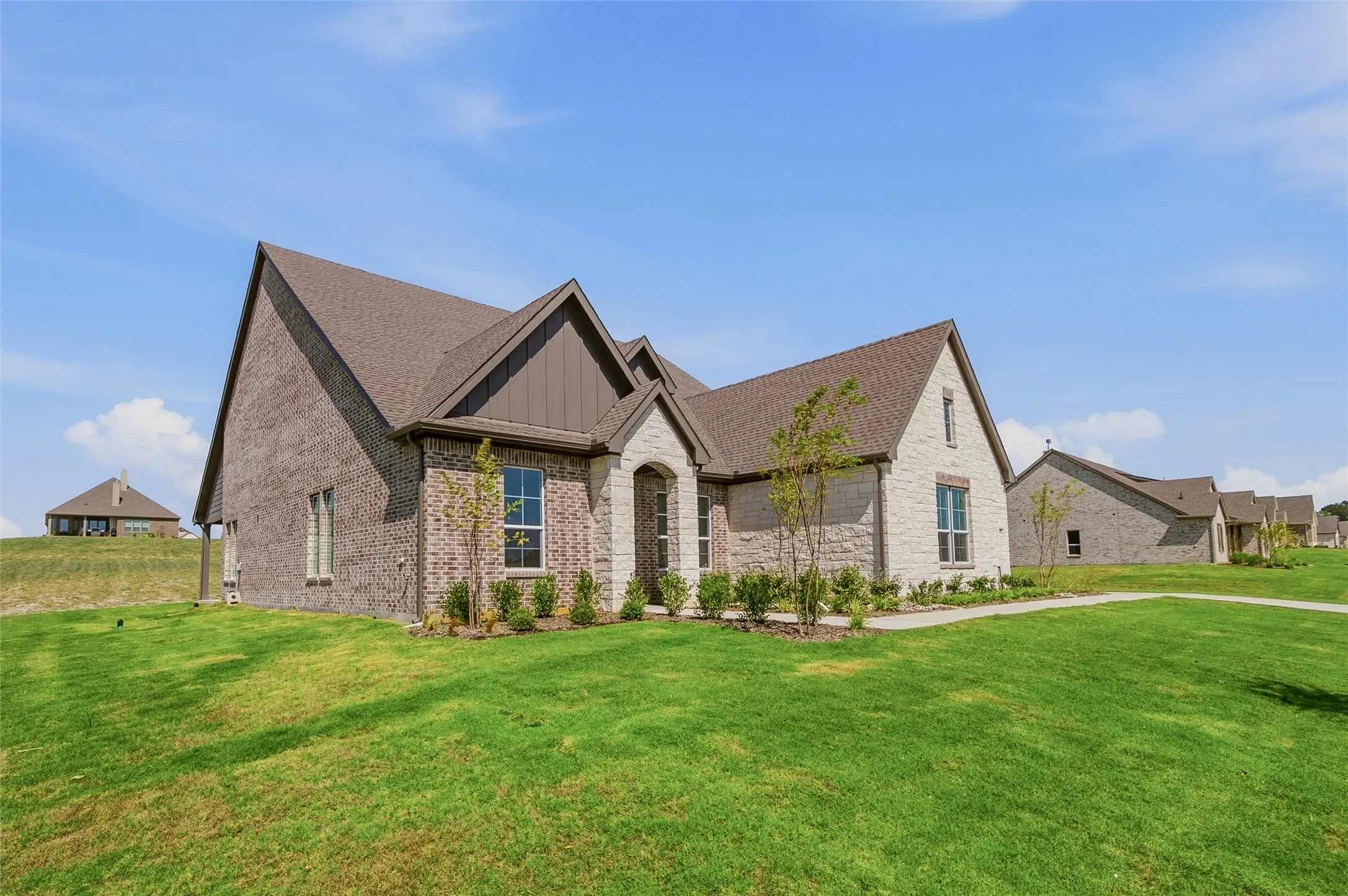 Brick and stone exterior featuring multiple gables, an arched entryway, and a covered porch