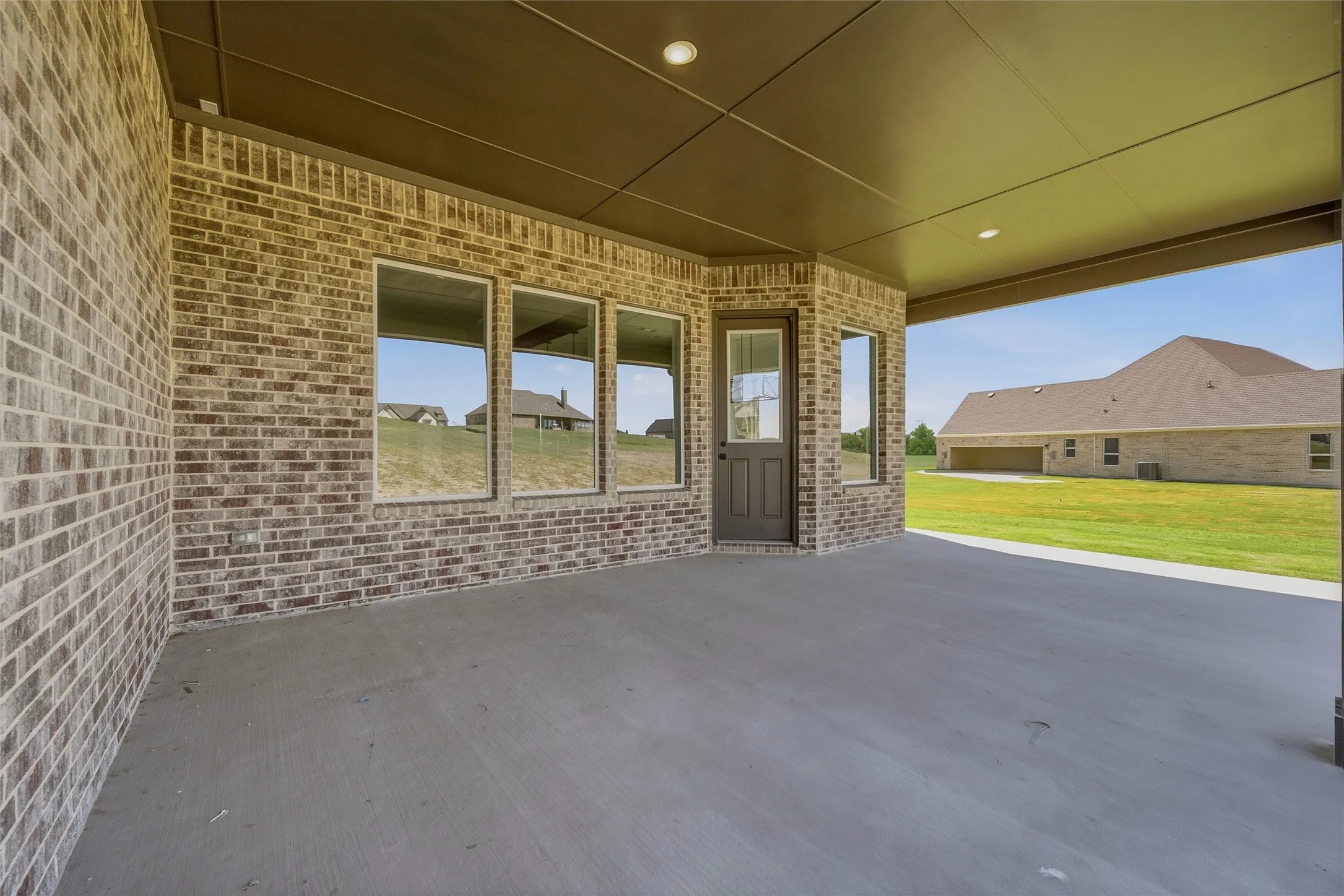 Covered patio with a concrete surface, recessed lighting, and brick exterior walls