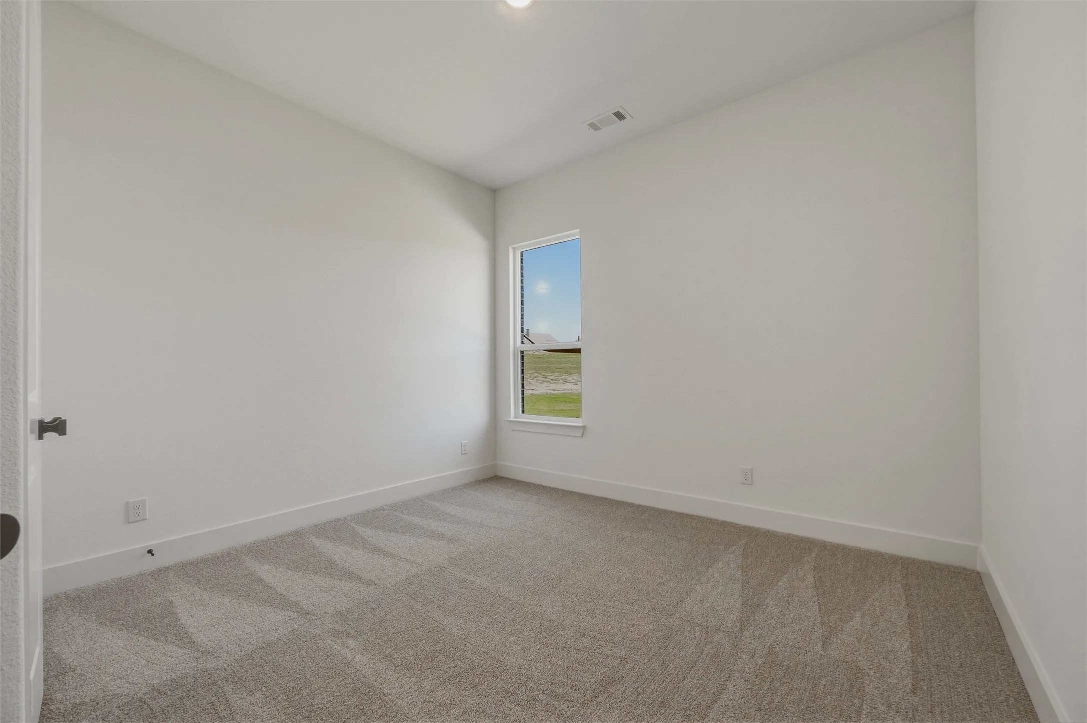 Neutral carpet flooring, white walls, single window, white trim