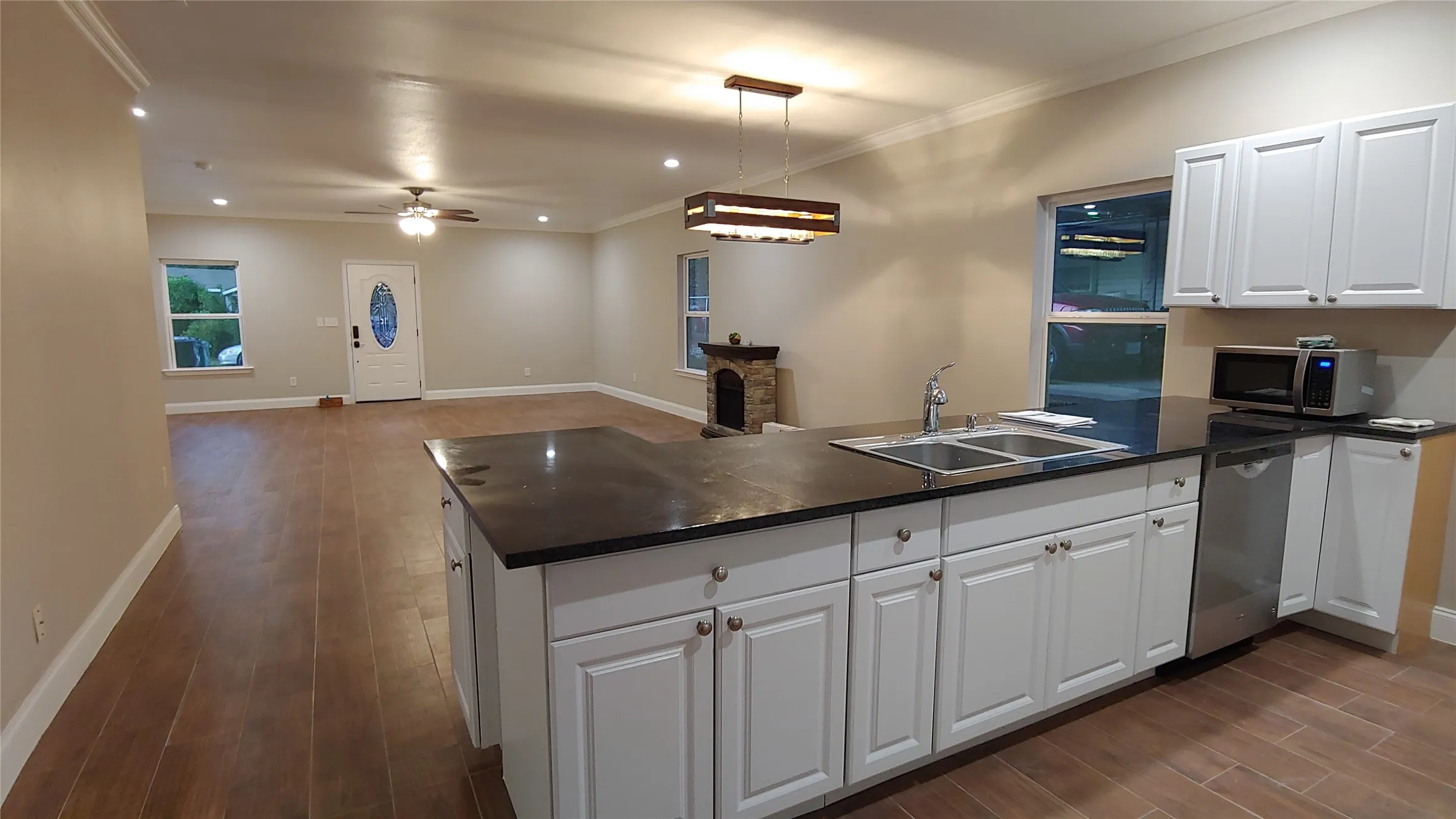 Open-concept living space featuring wood-finish flooring, recessed lighting, and crown molding