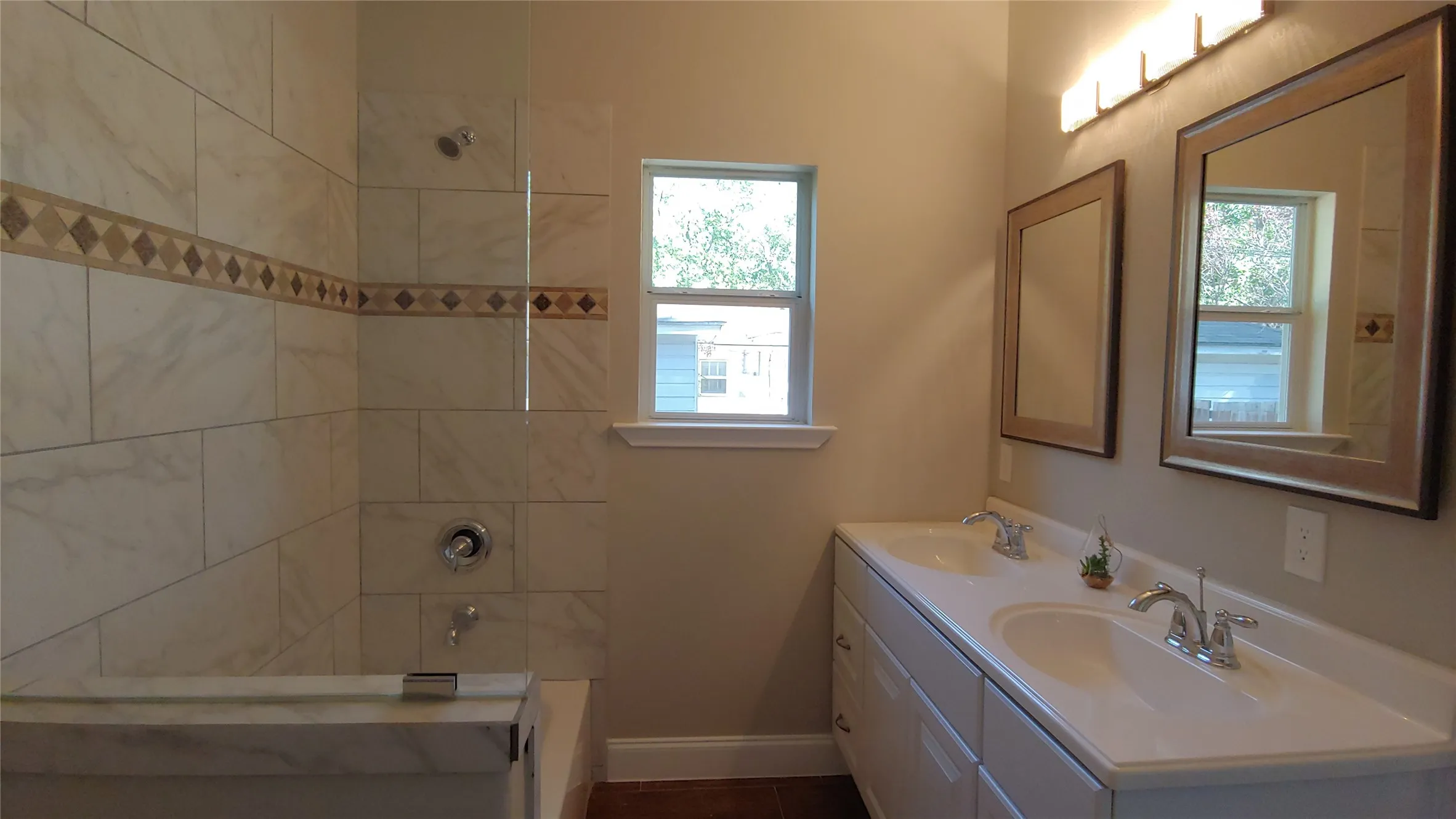 Bathroom with double sinks and shower/tub combo. Notice the lovely decorative tile.