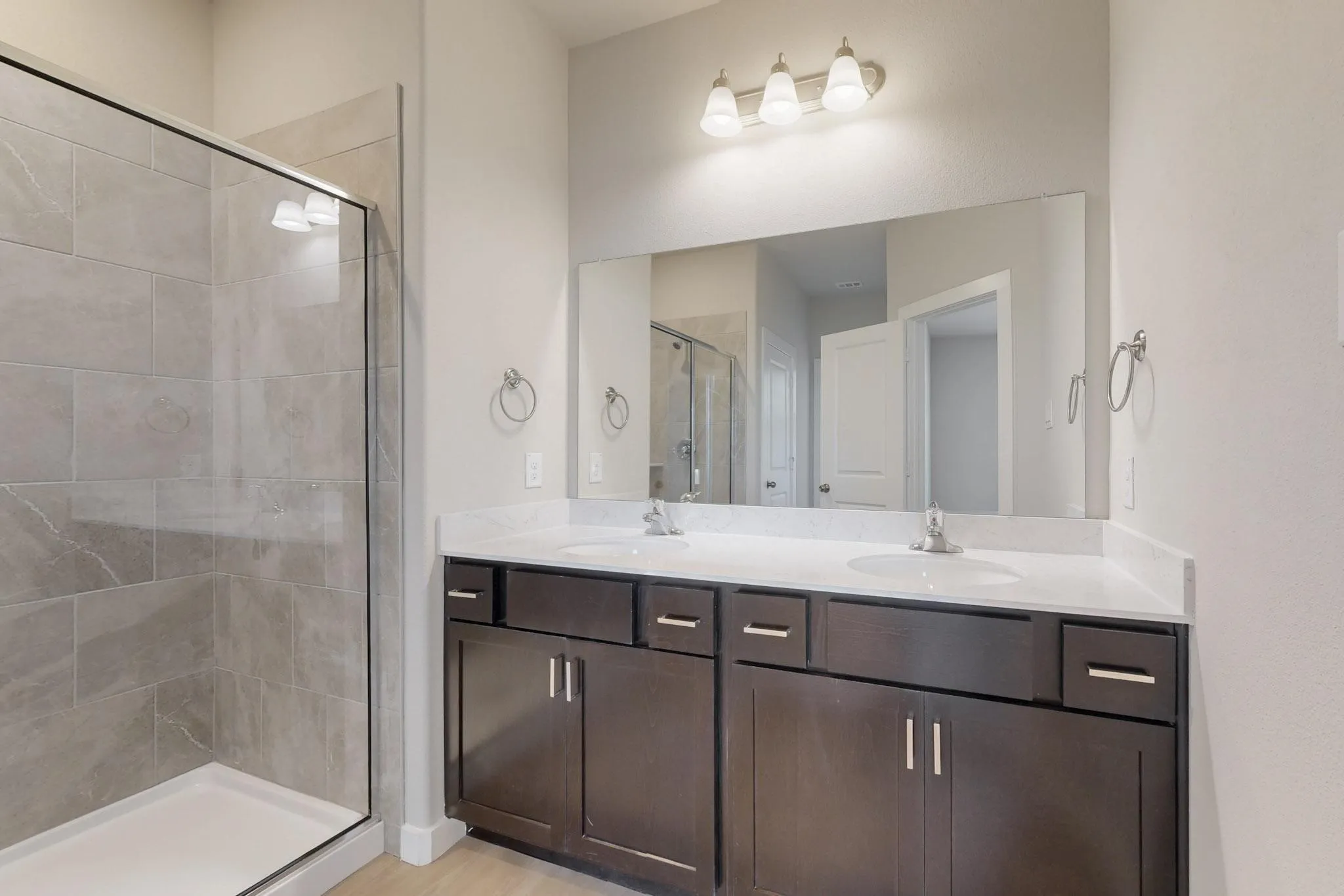 Bathroom with a shower stall, double vanity, and light wood-style floors