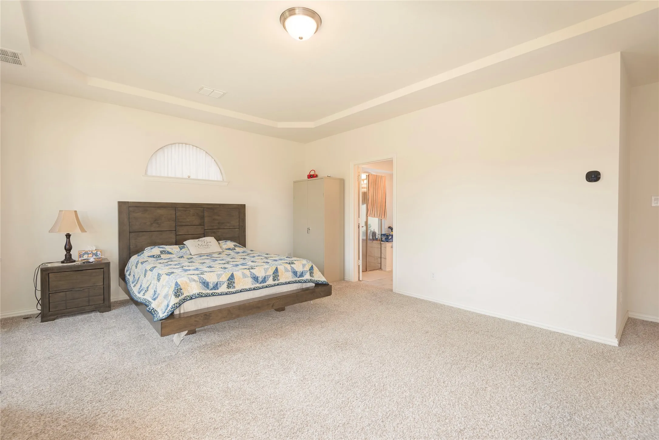 Carpeted room featuring a tray ceiling, recessed lighting, and an arched transom window