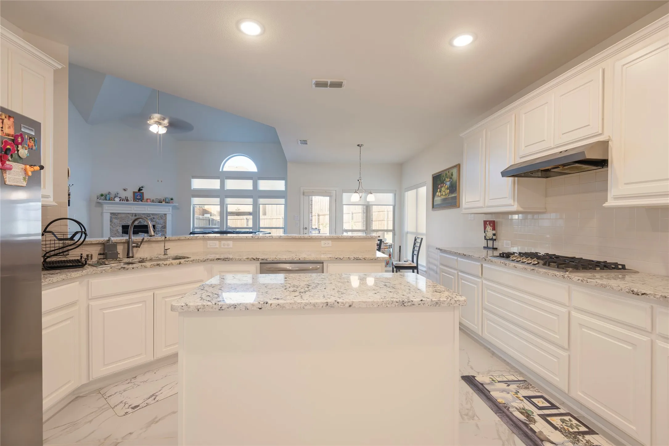 Kitchen featuring white cabinetry, light-toned countertops, a center island, a gas range, and a subway tile backsplash
