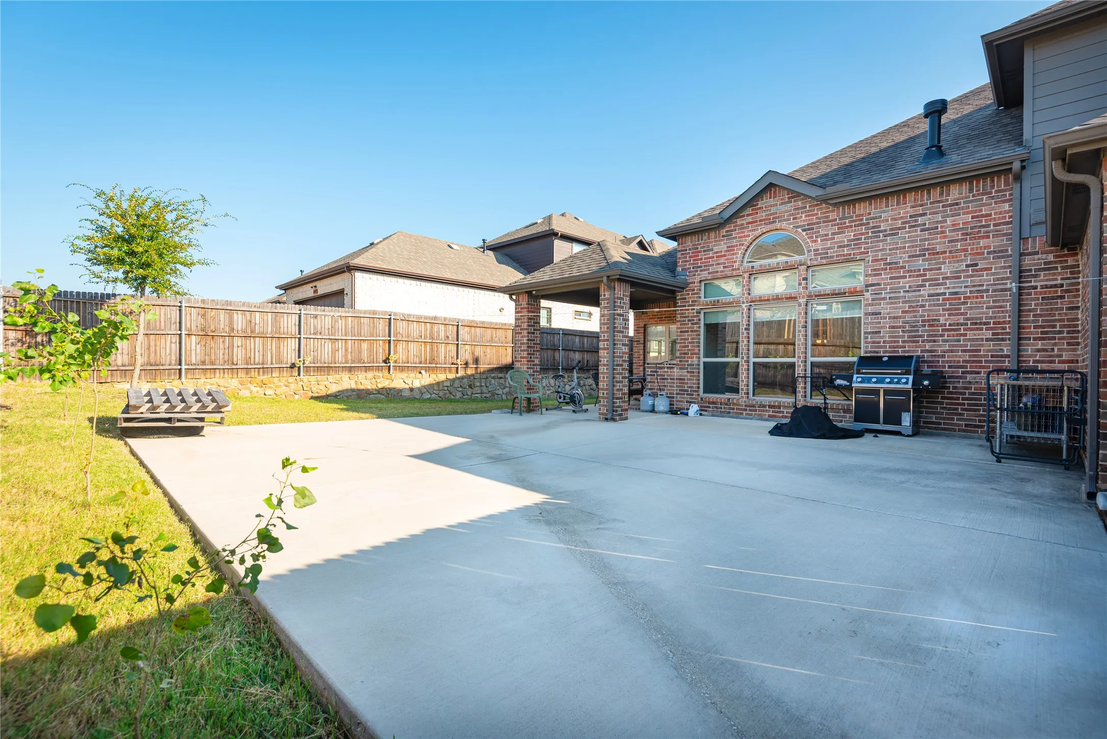 Expansive concrete patio area with a brick exterior and covered outdoor space