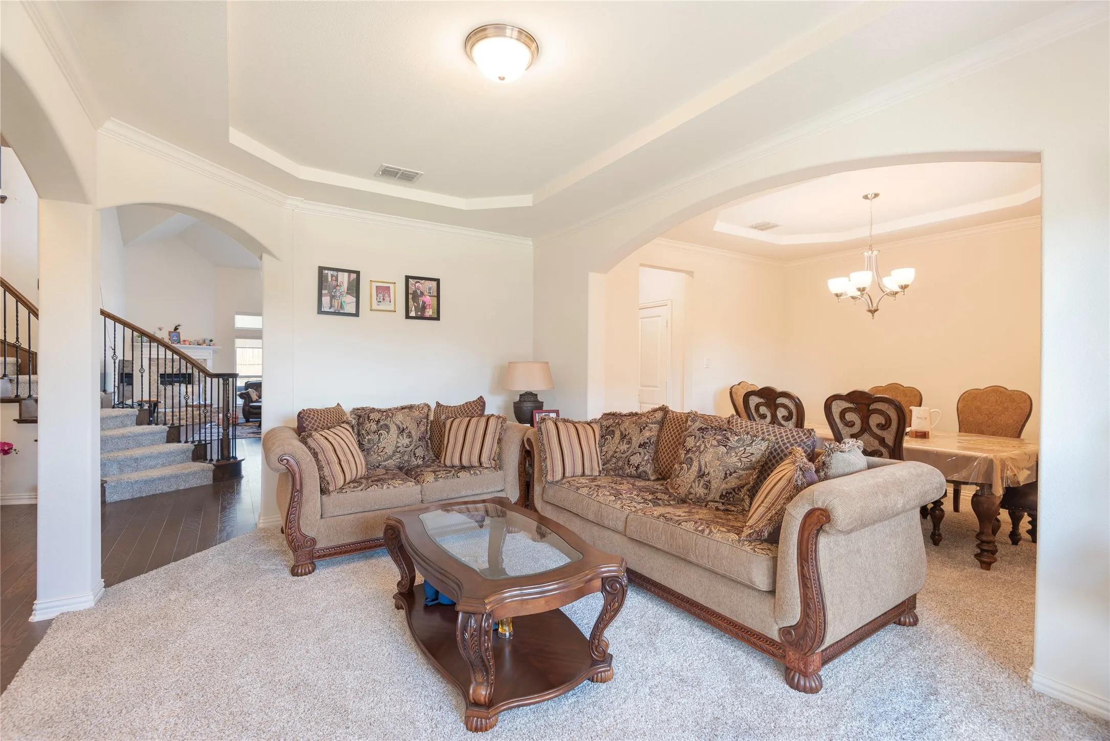 Living area featuring a layered tray ceiling and arched entryway