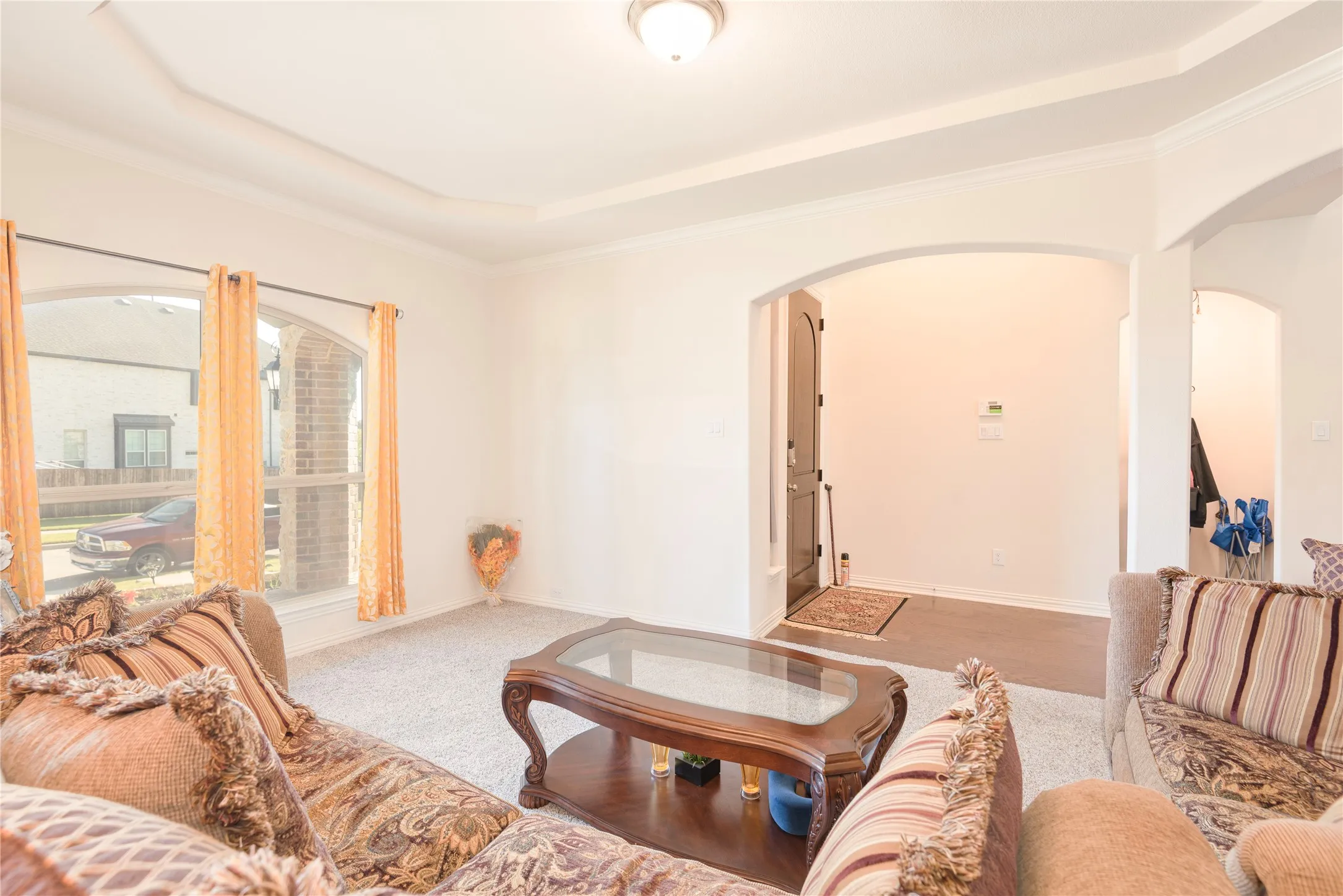 Living space featuring arched doorways and a tray ceiling