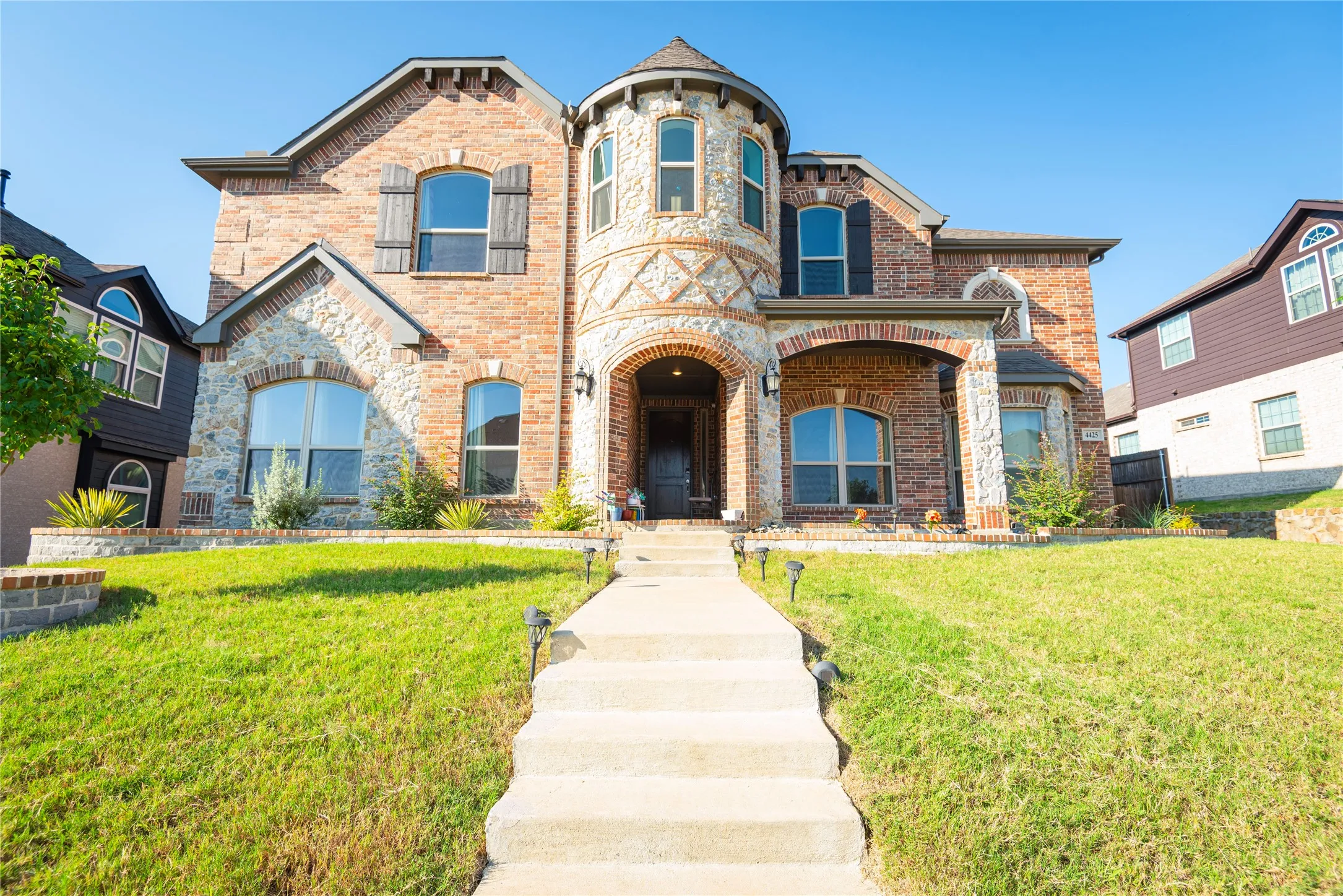Brick and stone exterior featuring an arched entry, a prominent turrett, and multiple arched windows