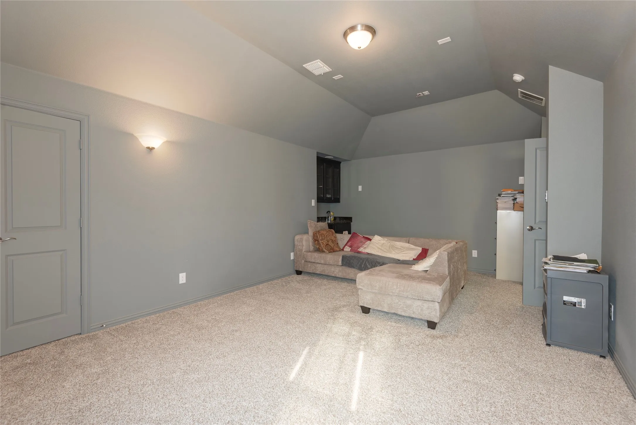 Carpeted room featuring a vaulted ceiling, recessed lighting, and a built-in wet bar with dark cabinetry