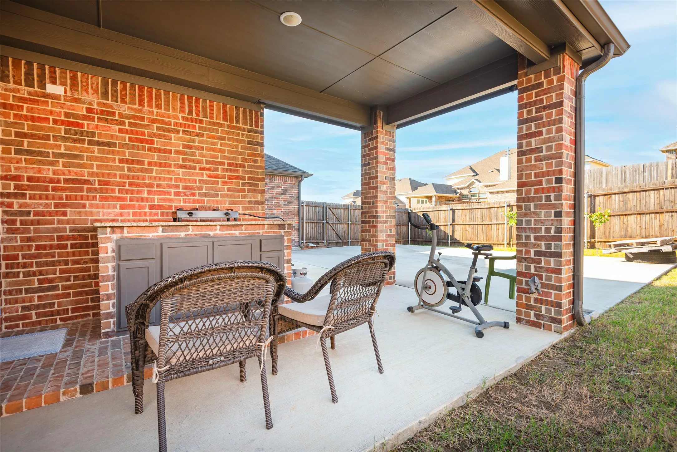 Covered patio featuring brick columns, recessed lighting, concrete flooring, and an outdoor kitchen with built-in cabinetry and a countertop