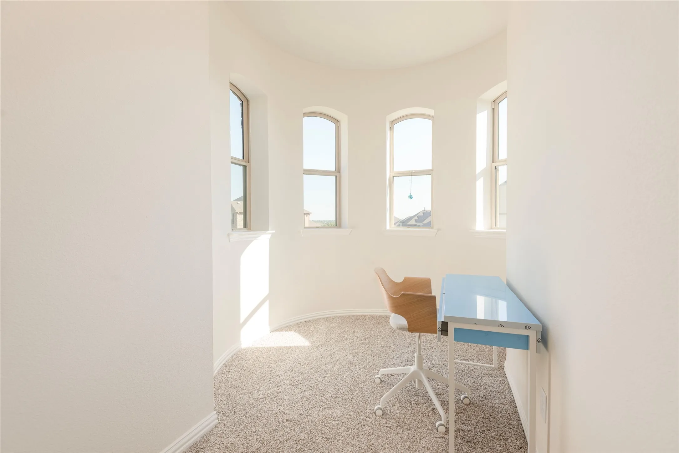 Curved architectural space featuring neutral carpeting and three arched windows