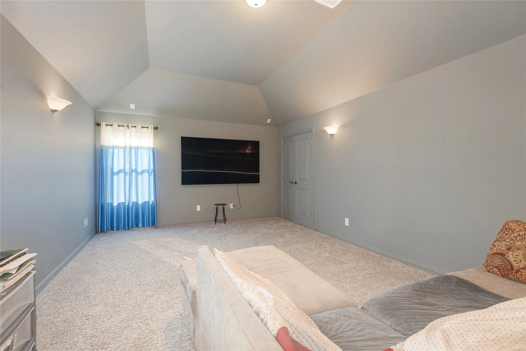 Carpeted room featuring a vaulted ceiling and light gray walls