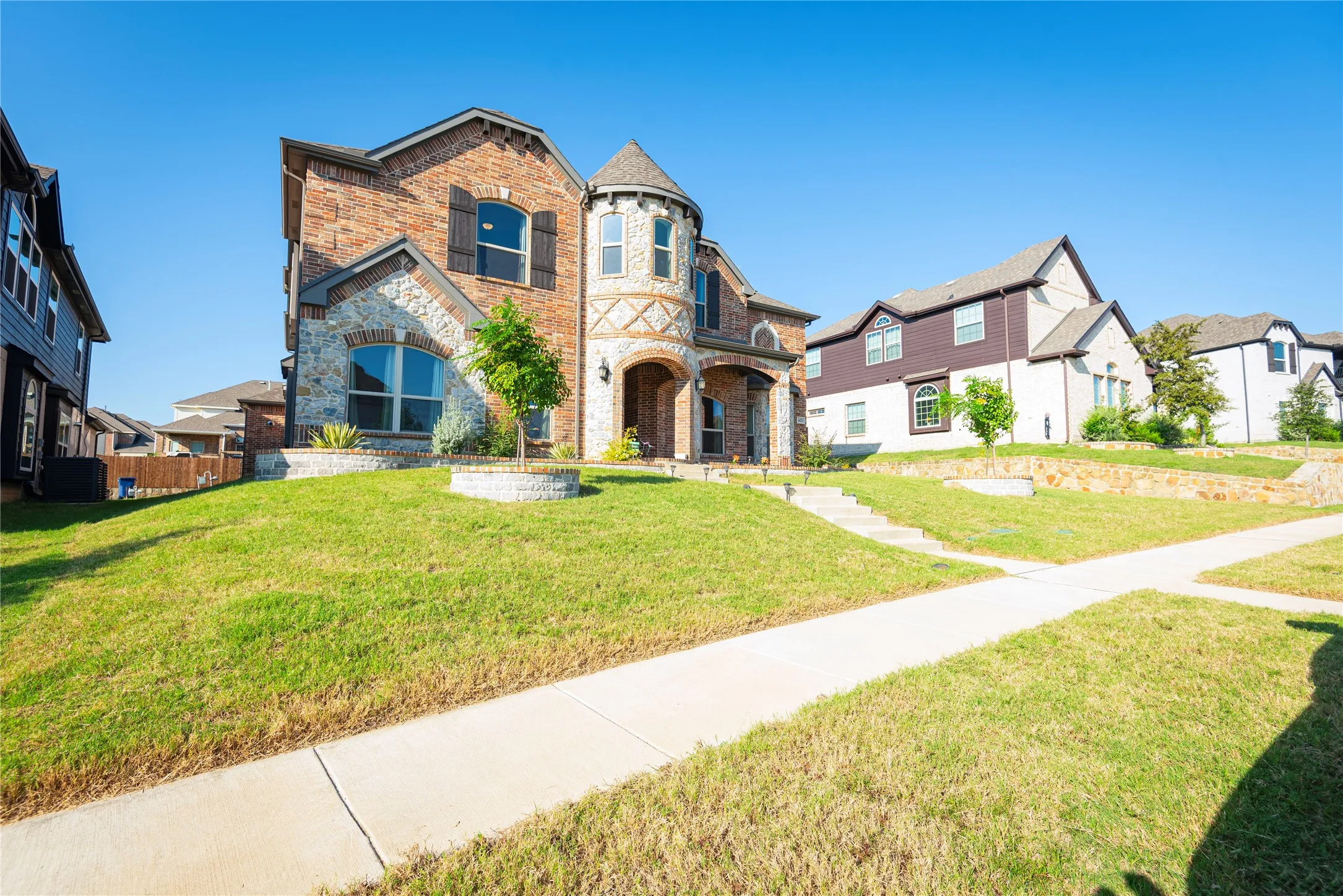 Two-story residence featuring a brick and stone facade with decorative shutters