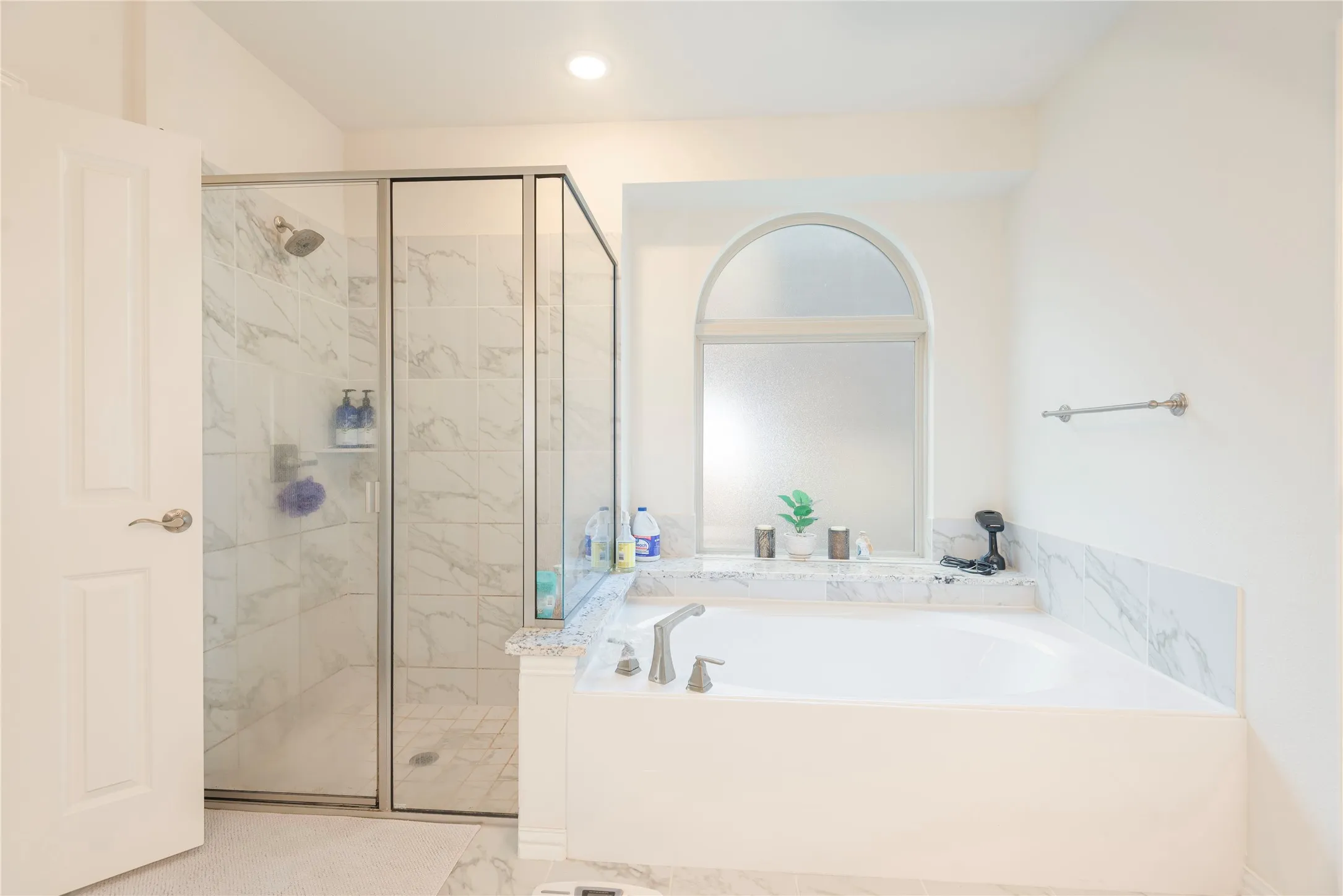 Spacious bathroom with a walk-in shower featuring glass enclosure and marble-look tile surround