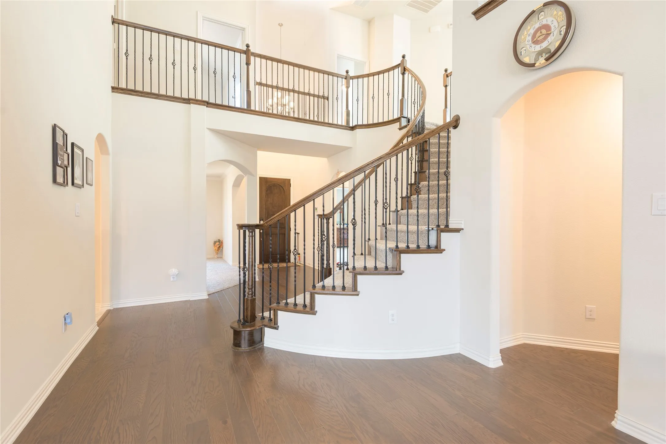 Grand entryway featuring a curved staircase with wrought iron balusters and wood-finish handrails