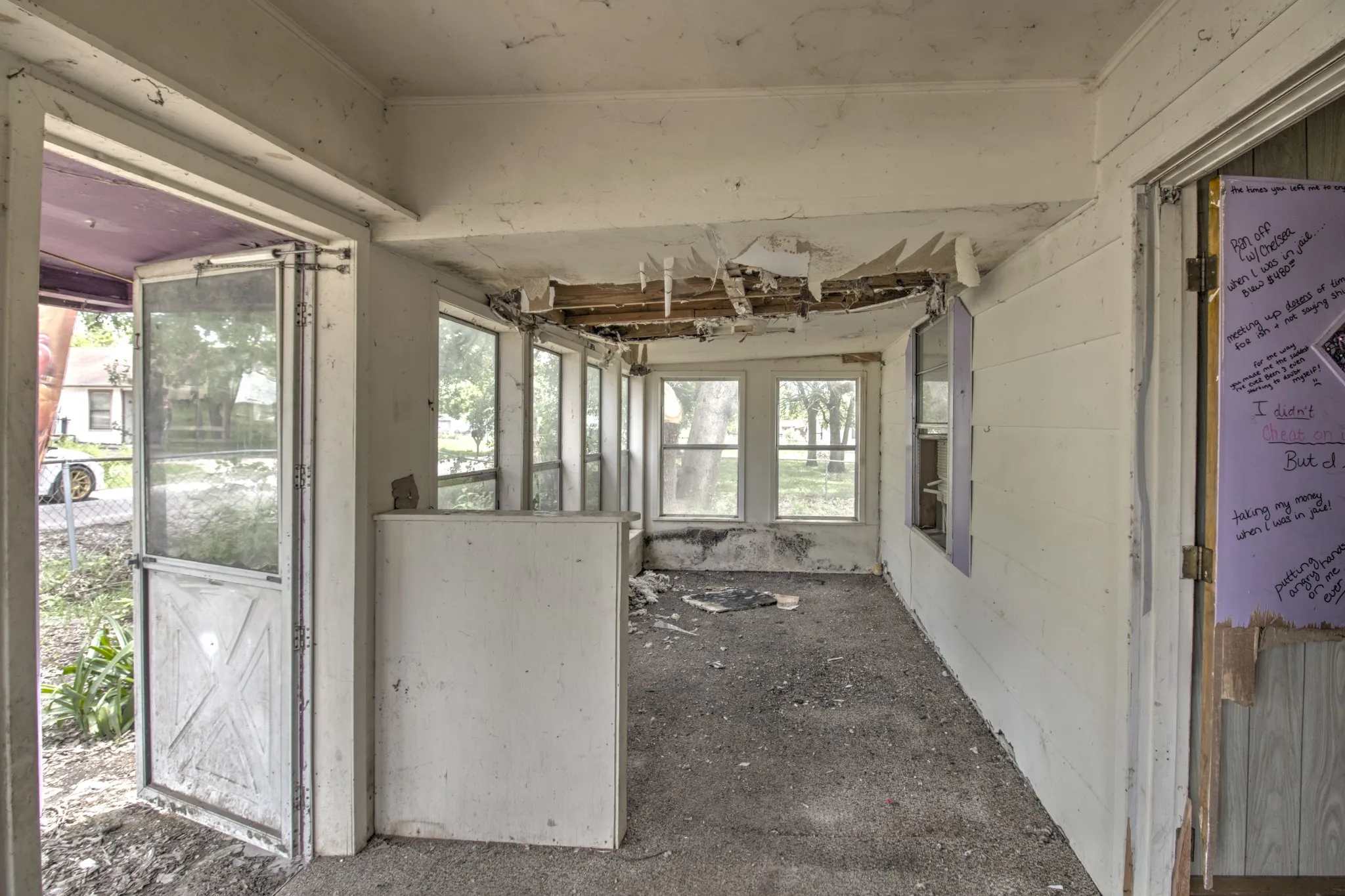 Enclosed patio space with multiple window openings, a screen door entry, and exposed ceiling joists