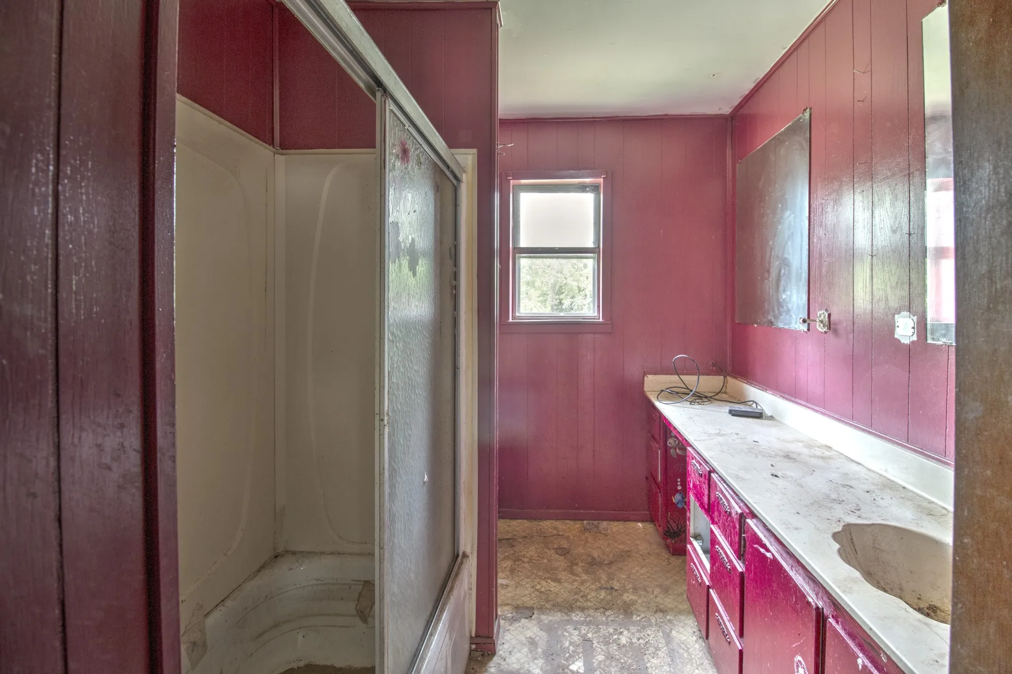 Bathroom featuring a stall shower with sliding frosted glass doors, a window, a long vanity with a built-in sink, and multiple vanity cabinets