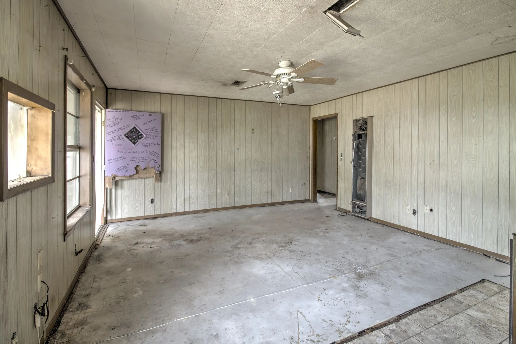 Interior space featuring textured ceiling, paneled walls, and a ceiling fan