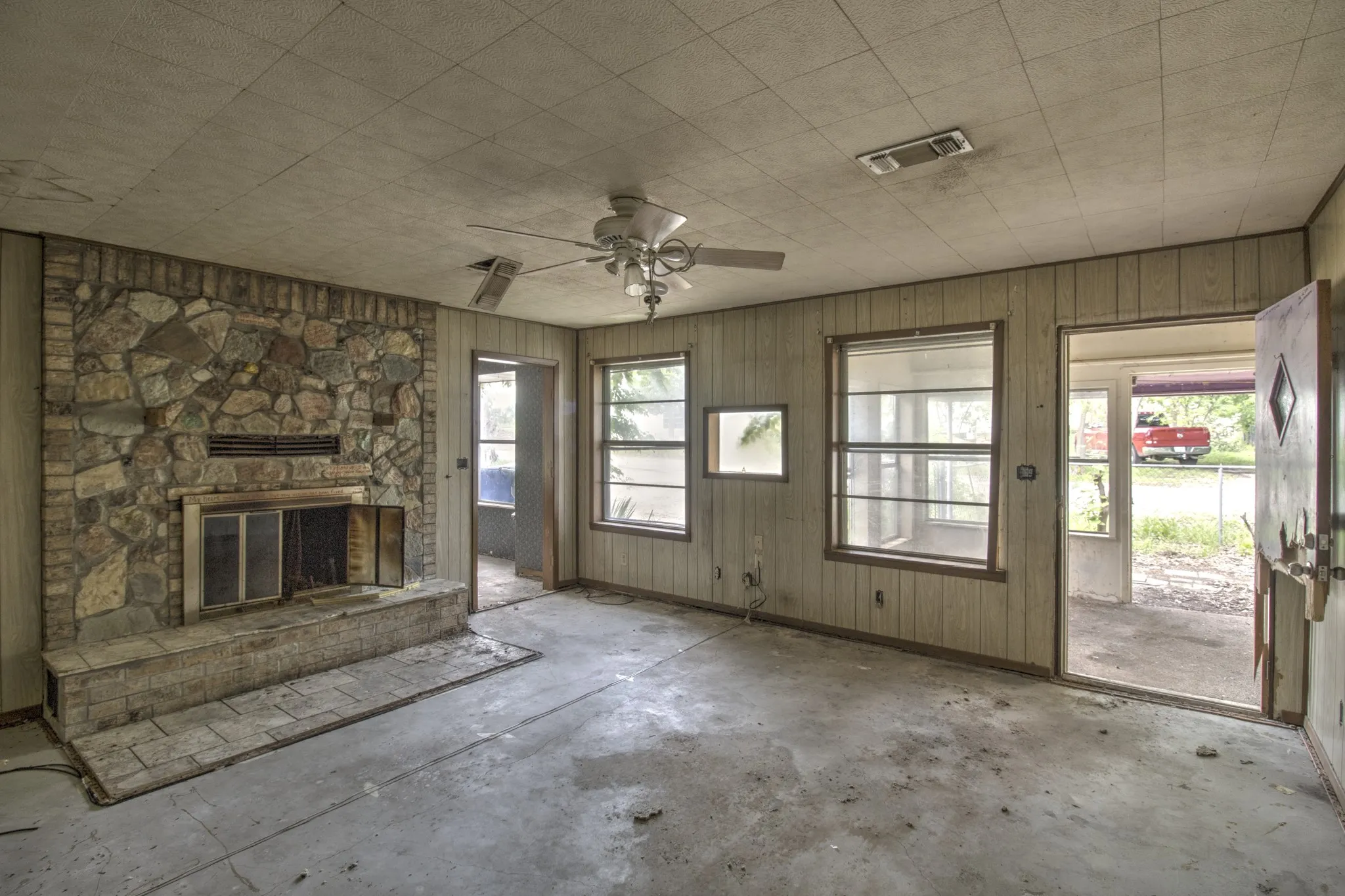 Stone and brick fireplace with a raised hearth, flanked by light wood paneling