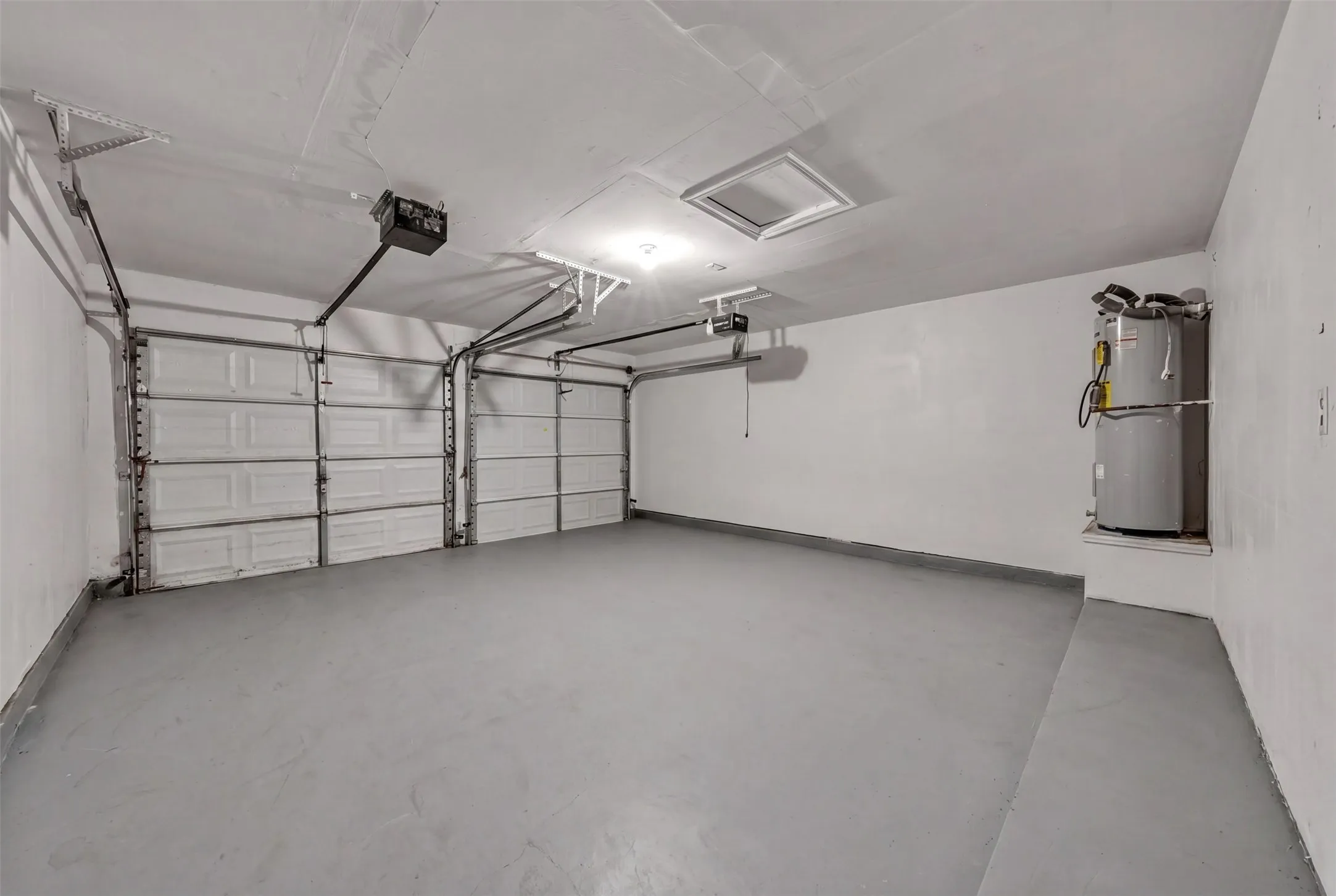 Spacious two-car garage featuring a gray epoxy floor finish and two automatic garage door openers